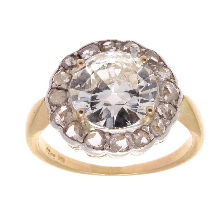 Forever in style, the halo design was first created in the Victorian era which is perfectly exemplified here. Featuring a 3.01 carat round brilliant cut diamond surrounded by numerous rose cut diamonds. Hand crafted in platinum and 18k yellow
