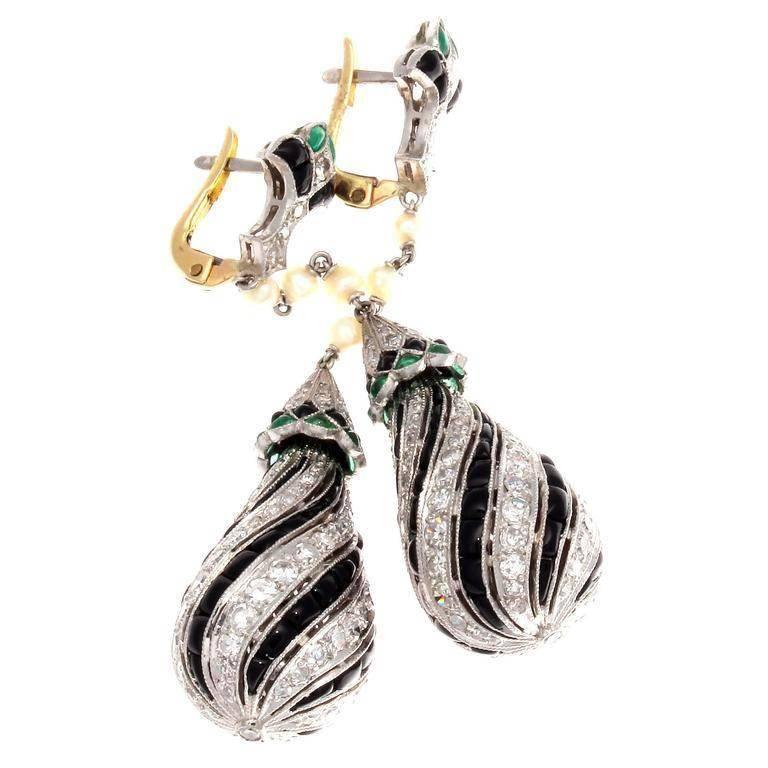 A modern creation of pure brilliance. Creating a blooming flower stud of vibrant green emeralds, jet black onyx and white clean diamonds that perfectly lead to long freely dangling creamy pearls flawlessly descending in to the chandeliers of