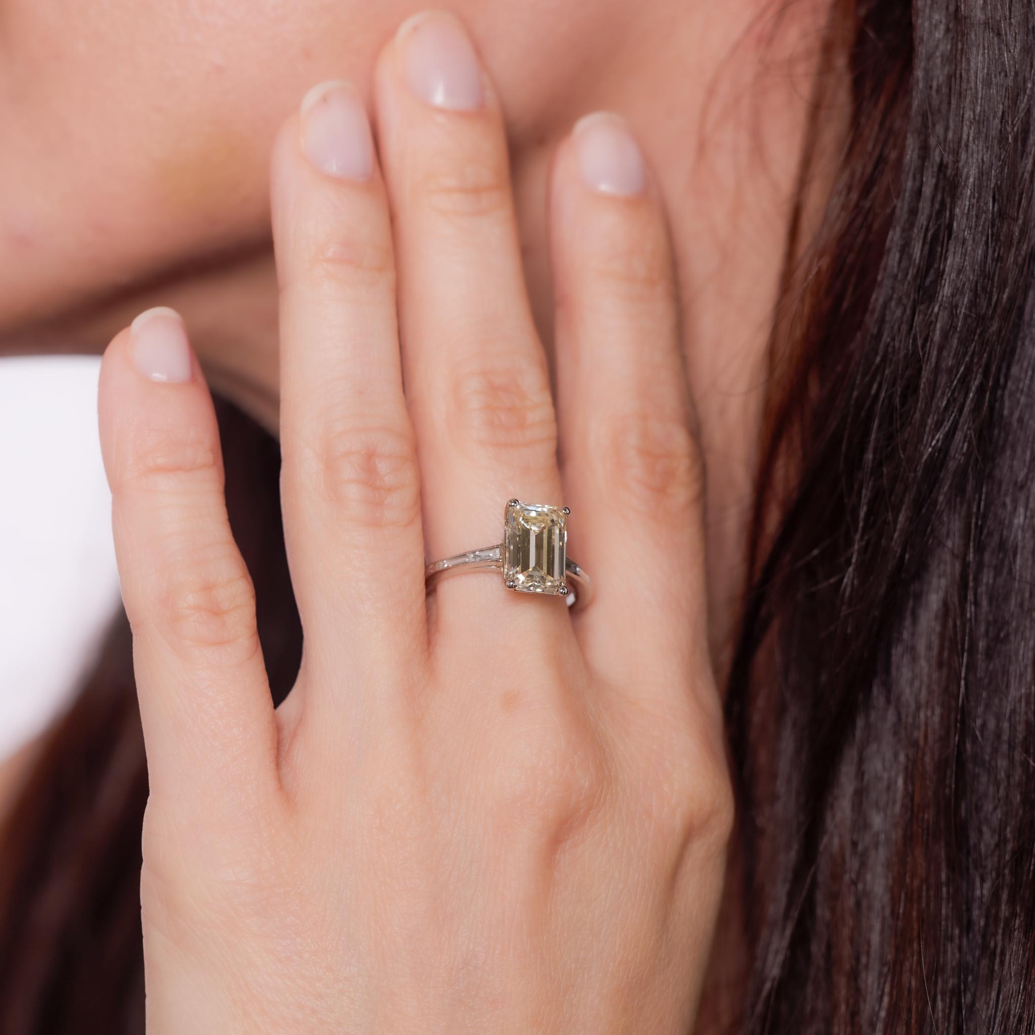 Crafted in the 1960s, this Mid-Century platinum engagement ring centers a GIA-certified 3.21-carat emerald cut diamond, graded N color and VS1 clarity. The elongated step-cut sparkles with vintage allure, flanked by two baguette cut diamonds