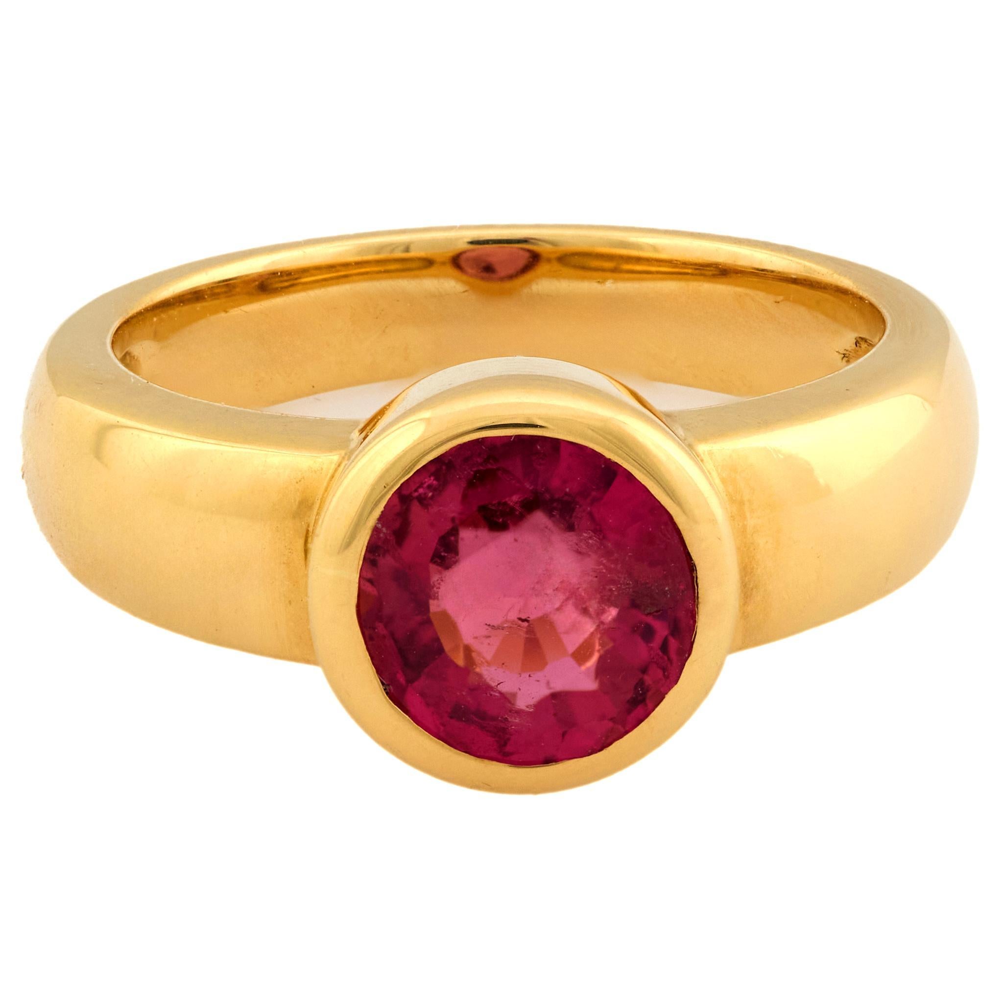 Cette bague vintage des années 1990 présente une tourmaline rose ronde de 1,20 carat, taillée en brillant, sertie dans un riche or jaune 18 carats. La teinte rose saturée de la pierre centrale rayonne de chaleur et d'éclat, rehaussée par le design
