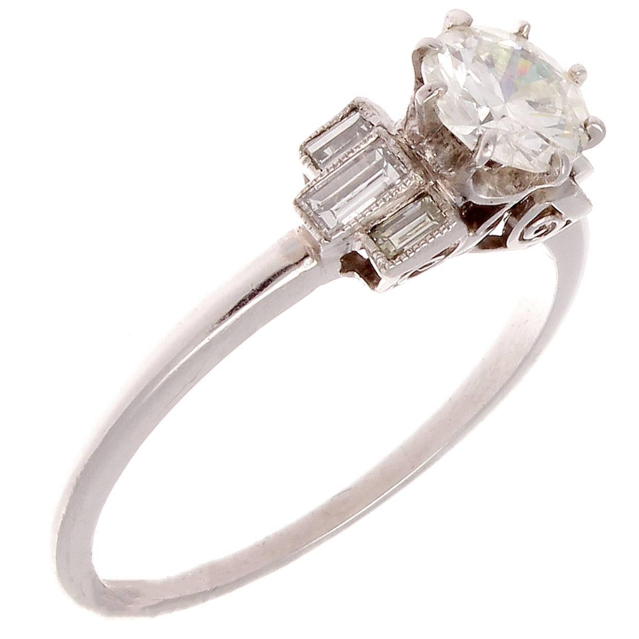 The allure of the Art Deco time period has inspired the creation of this lovely engagement ring. Featuring a center diamond weighing 0.58 carats and is H color, SI1 clarity. Accented by a spray of baguette cut diamonds on either side. Crafted in