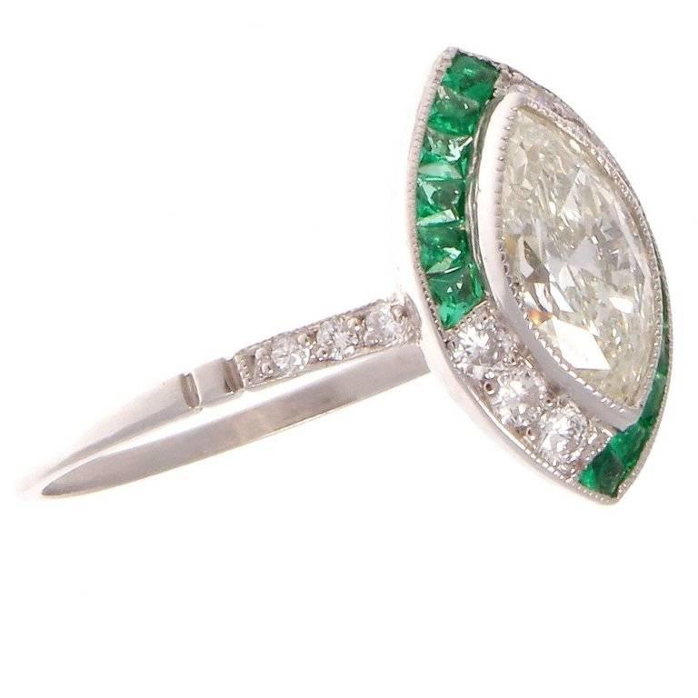 The well cut marquise diamond weighs 0.94 carats, approximately H color and VS clarity. The French cut emeralds are expertly cut to fit the ring and the forest green color is consistent throughout. The ring is Art Deco inspired and the design and