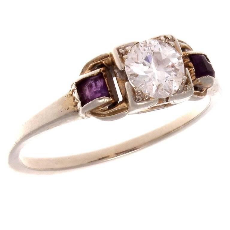 Created with an old European cut center diamond that is accented on either side by a vibrant purple amethyst. Hand crafted in 14k gold.

Ring size 5 3/4 and may be re-sized to fit.