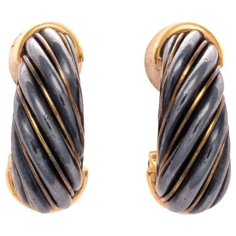True sophistication of style from Cartier. Featuring twisting lines of chrome hematite perfectly crafted in glistening 18k gold. Signed Cartier and numbered.
