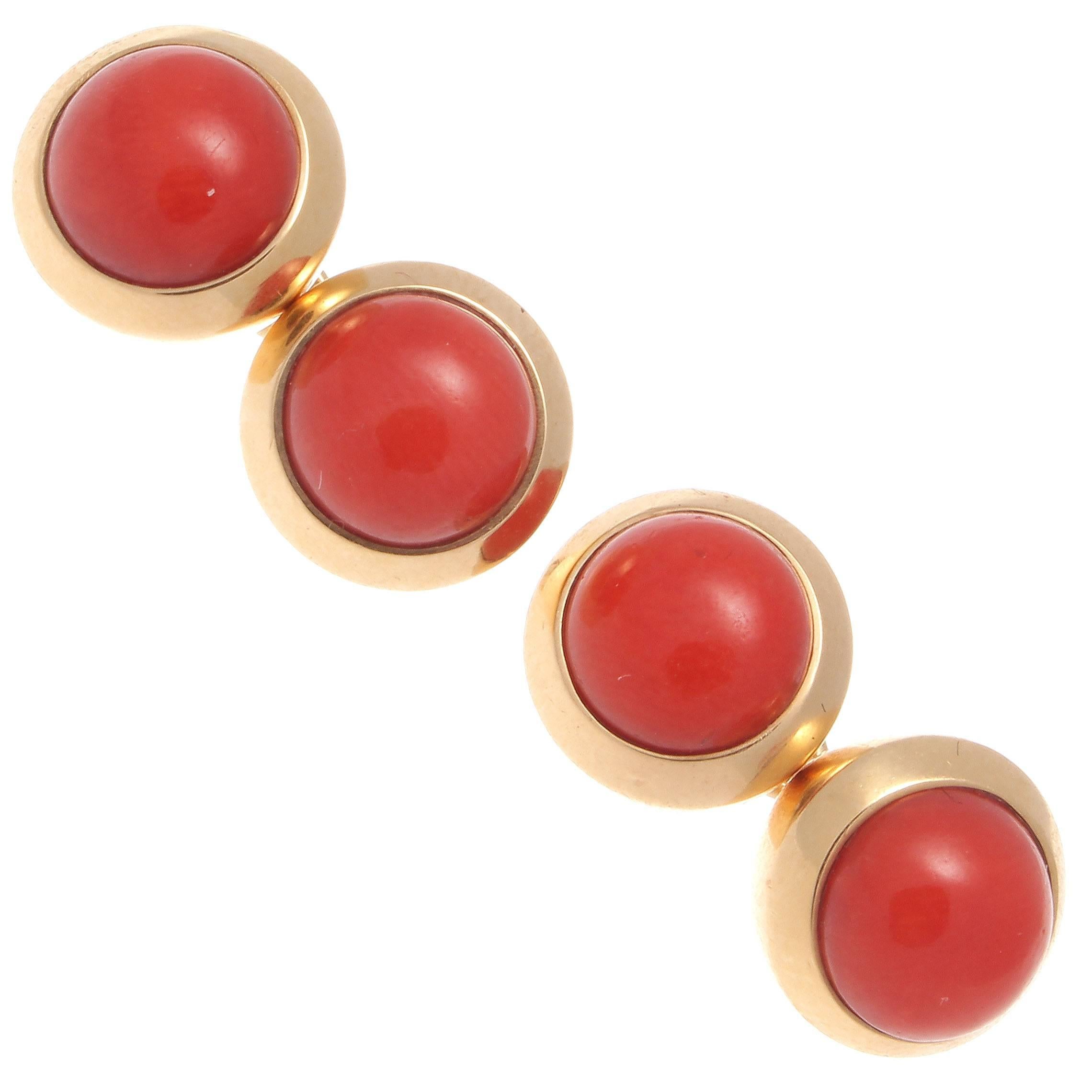 Elegance and pure design is innate in all of Cartier's creations. Featuring bright cabochon cut reddish orange coral bezel set in 18k glistening yellow gold balls. Signed Cartier.