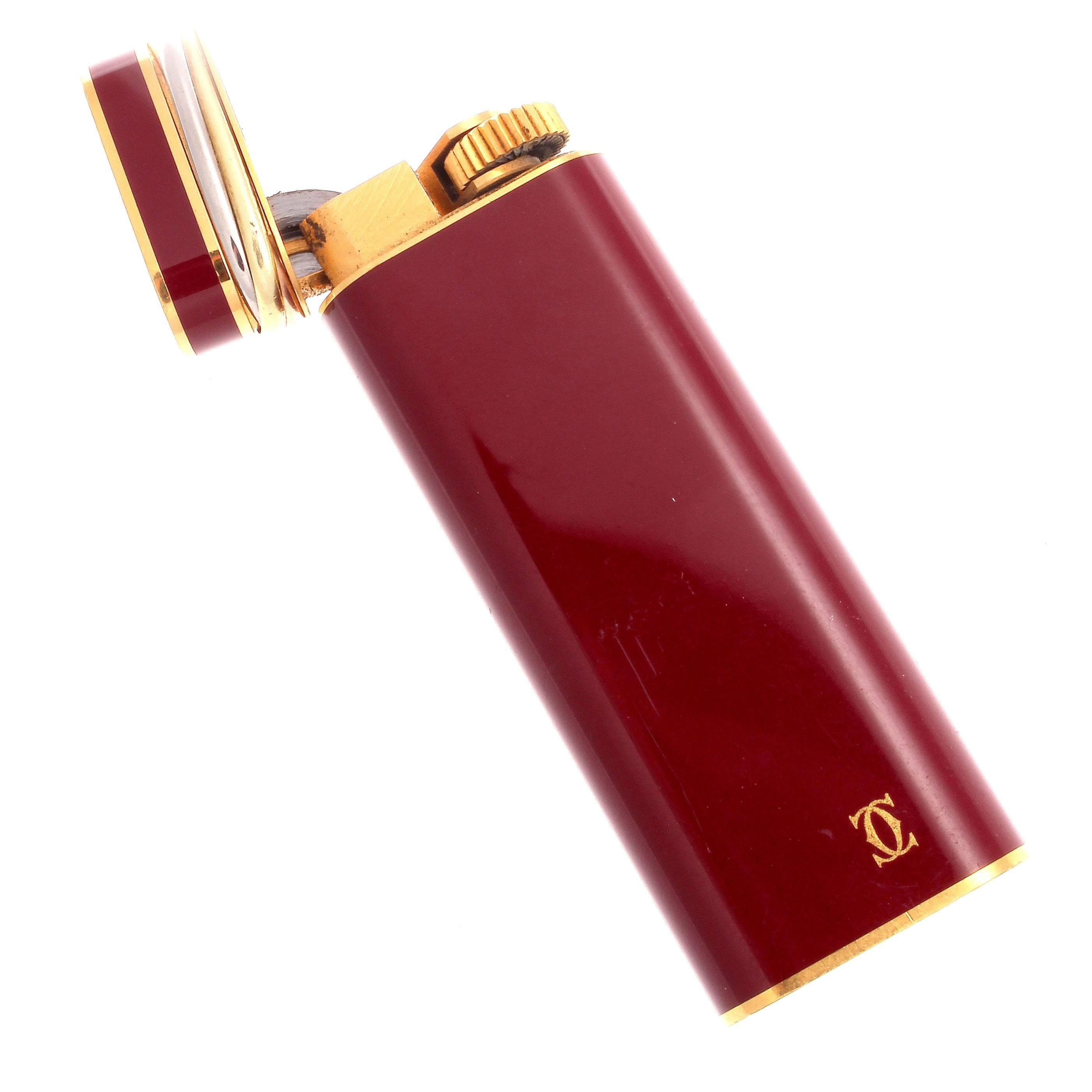 A chic, elegant accessory by the always stylish French jewelry house, Cartier. Featuring one of their most famous designs, the trinity, which is perfectly complimented by the burgundy red. Signed Cartier and numbered.