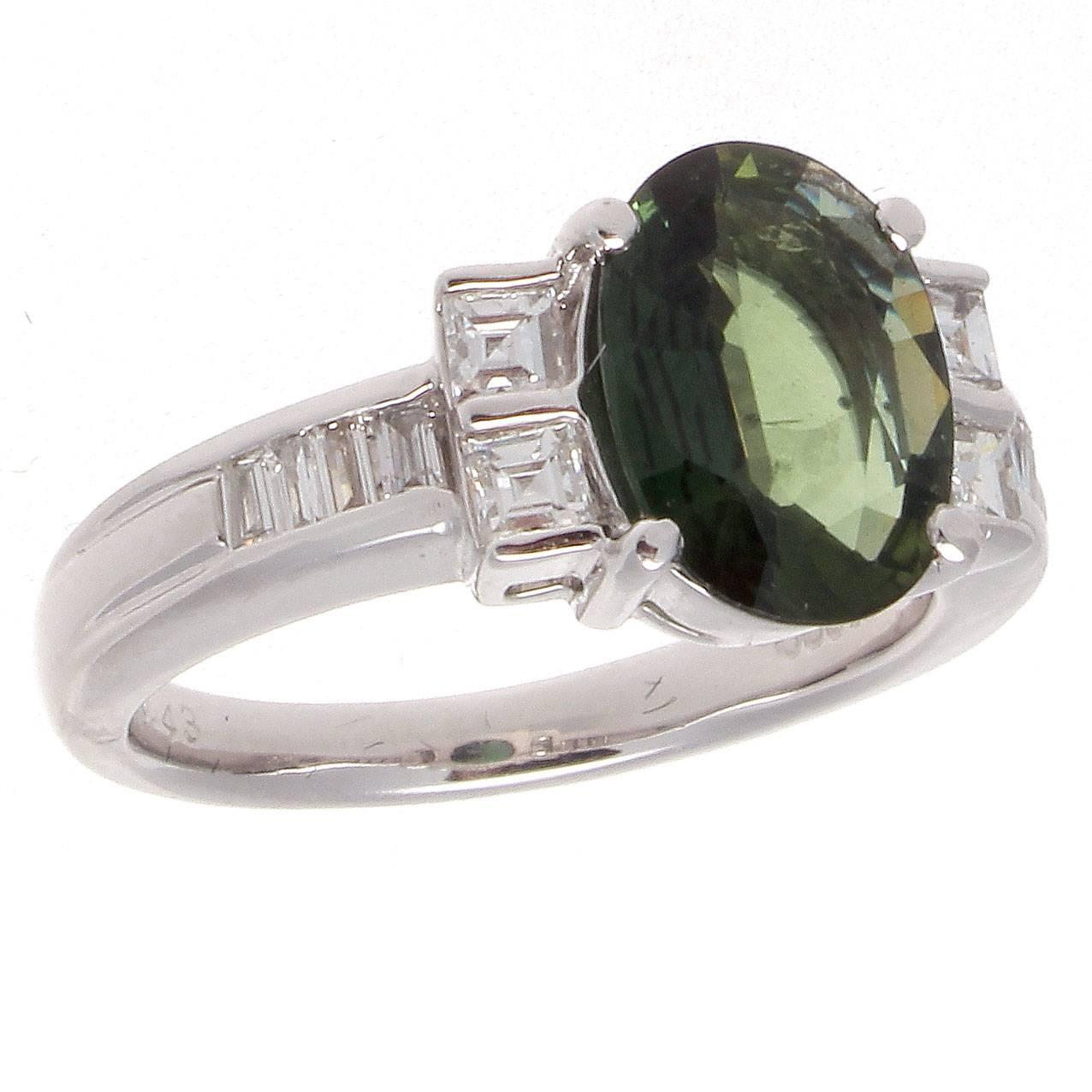 Colored stones are part of the new wave of modern nontraditional engagement rings, setting you apart from the rest of the crowd. Featuring a vibrant forest green sapphire that is accented by  an array of colorless emerald cut diamonds varying in