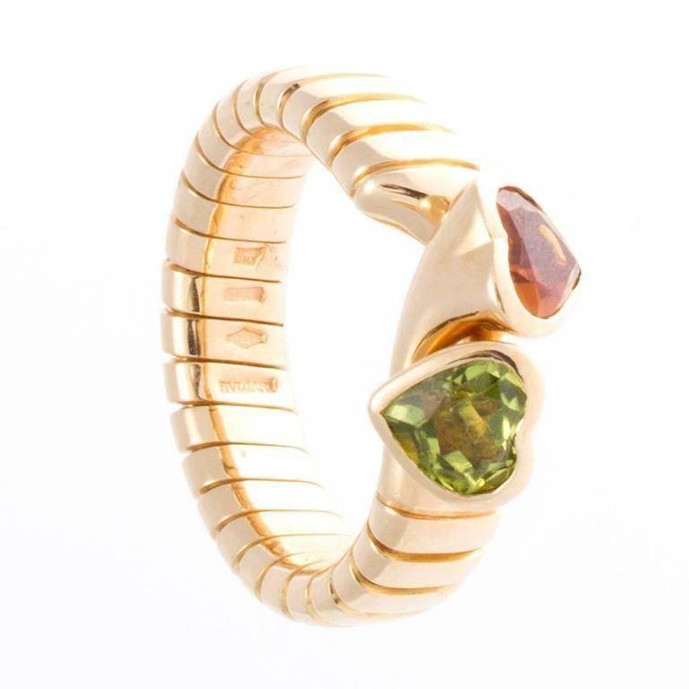 Stylish and colorful from Bulgari. Designed with interlocking hearts of green peridot and a golden citrine set amid ribbed sections of 18k gold. Signed Bvlgari. 

Ring size 6 with flexibility to fit bigger sizes.