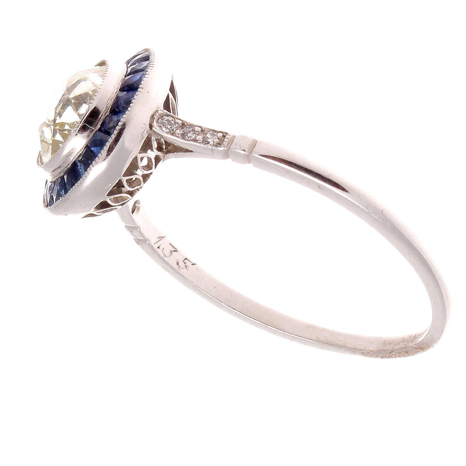 The 1930's is regarded as the golden era of jewelry and has influenced designers to recreate the jewelry from this remarkable time. Featuring a 1.35 carat diamond that is surrounded by a halo of navy blue sapphires. Crafted in platinum.