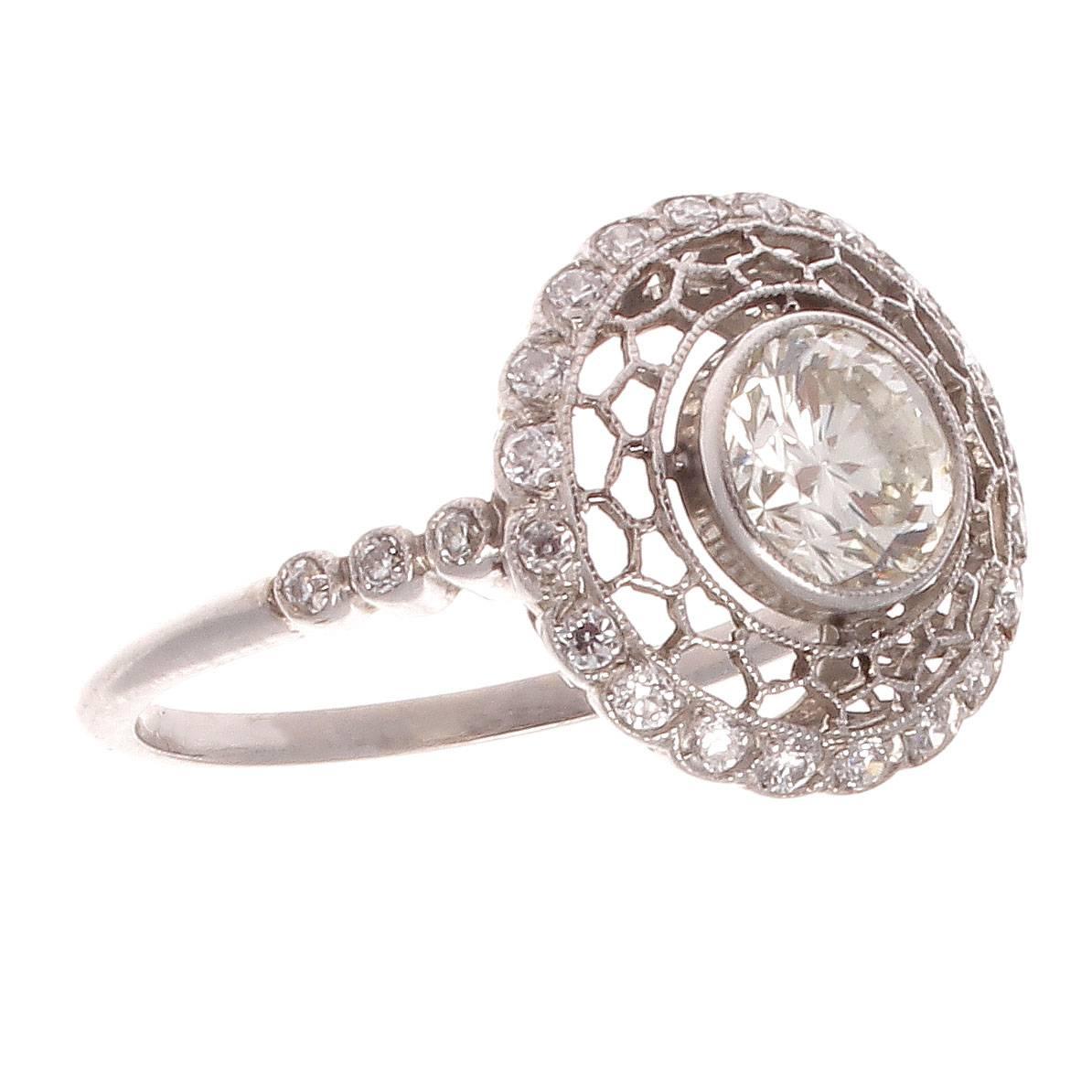 The allure of the Art Deco time period has inspired the creation of this eye catching ring full of intricate craftsmanship and superior design. Featuring a center diamond weighing 0.76 carats that is surrounded by a blooming flower of hand carved