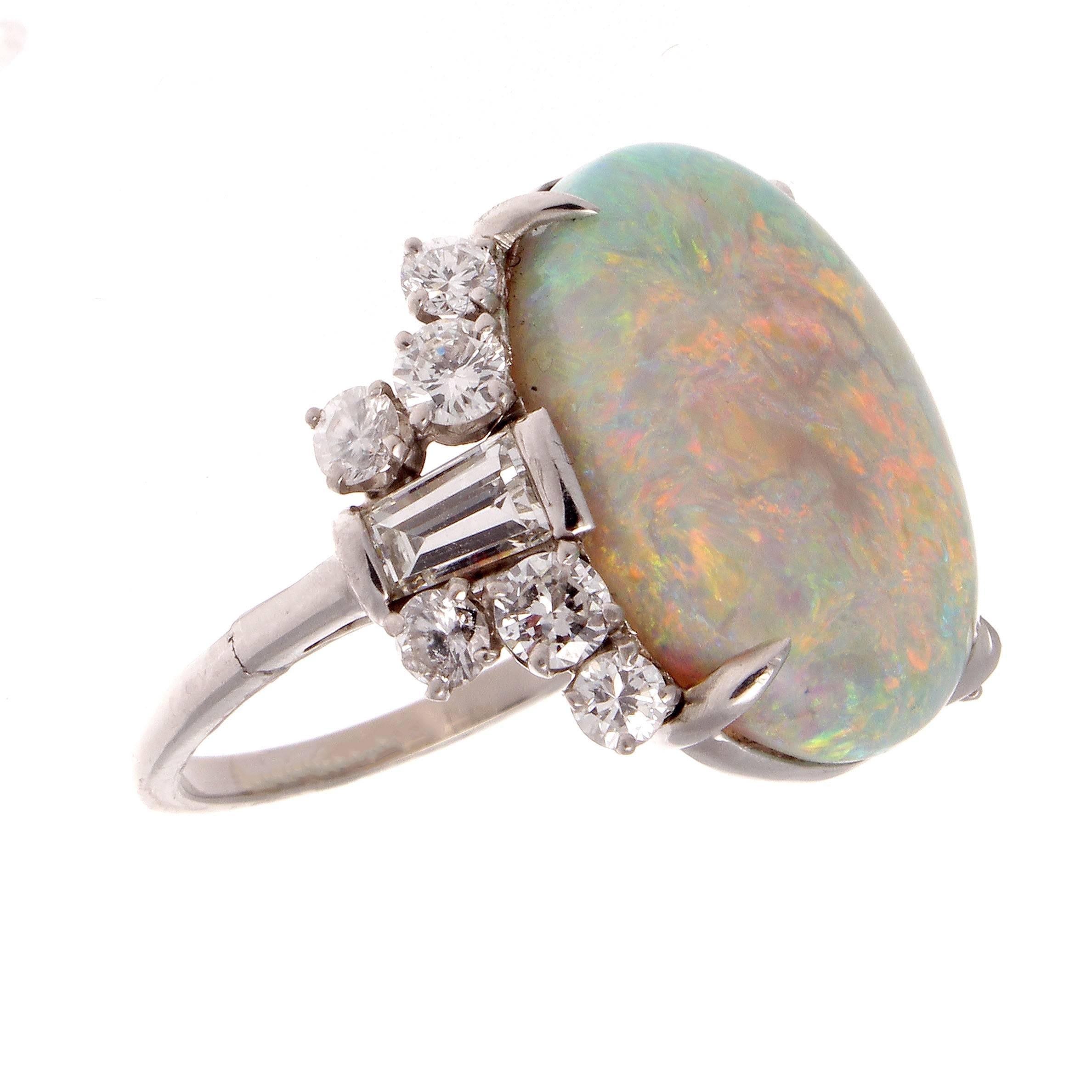 A late retro Opal ring displaying many vibrant colors.  Featuring a 10.88 carat Opal beautifully set in a very stylish ring.  Accented on either side by flares of baguette and round cut diamonds that are E-F color, VS clarity. Hand crafted in