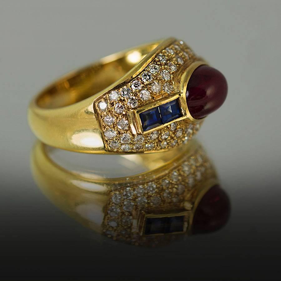 18K Ring with 1 oval cabochon Ruby weighing 2.77 carats and 4 square cut sapphires weighing 0.57 carats and 28 pave set round brilliant diamonds weighing 0.72 carats.
