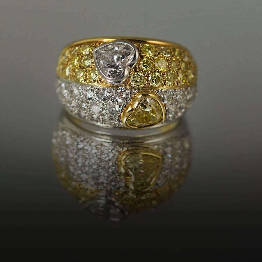 Hand Fabricated Ring by Keith Davis for Thayer Jewelers. Containing one GIA certified Intense Yellow heart shape diamond weighing 0.63 carats and one EGL certified E color diamond weighing 0.70 carats. In addition there is 1.29 carats of pave set