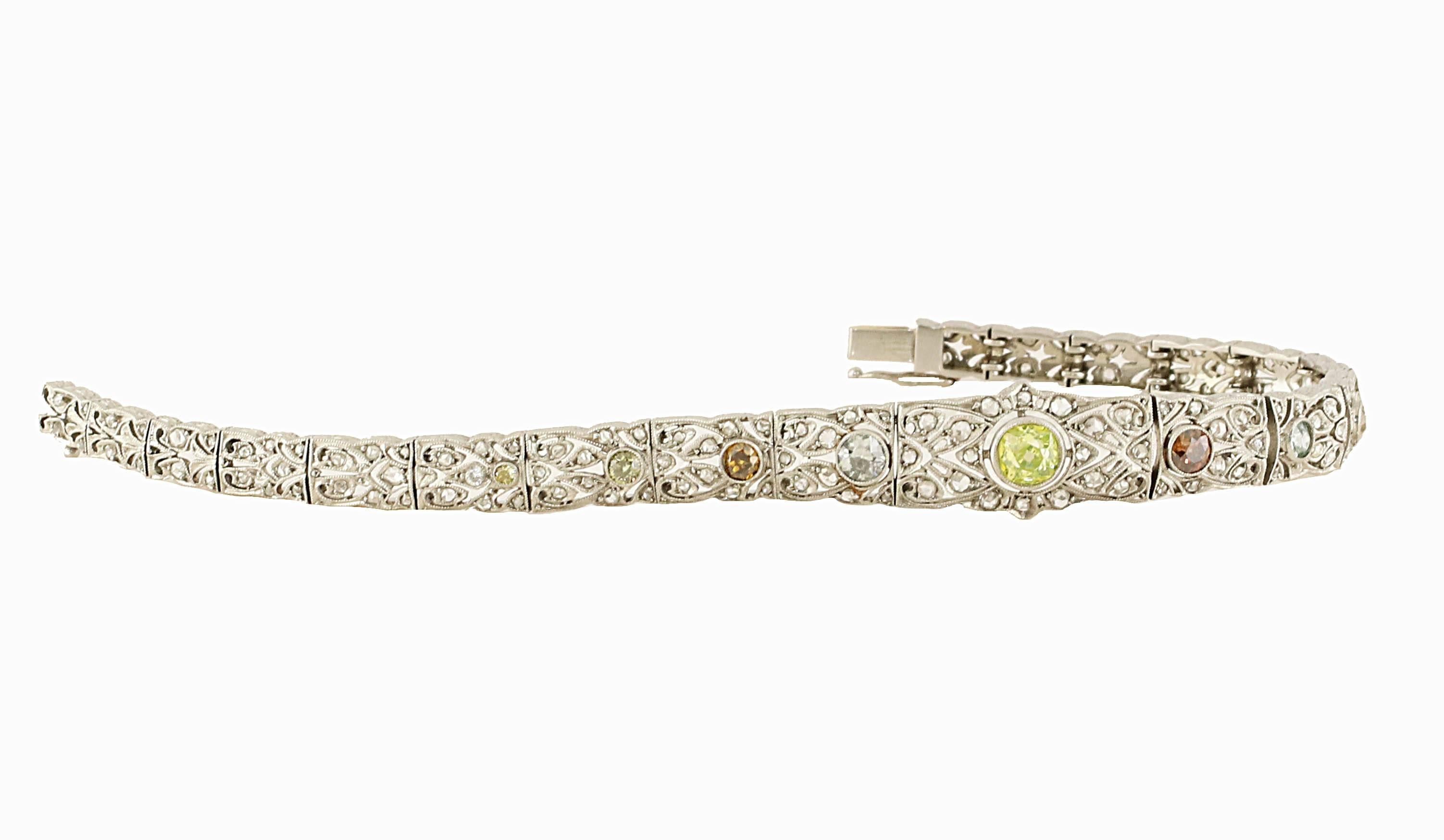 A timeless 18kt art-deco bracelet with intricate detail and workmanship . There are 9 exquisite NATURAL colored diamonds. The colors range from shades of yellow, oranges and blue. 
The center stone is about +/- 0.50ct. 
small white diamonds total