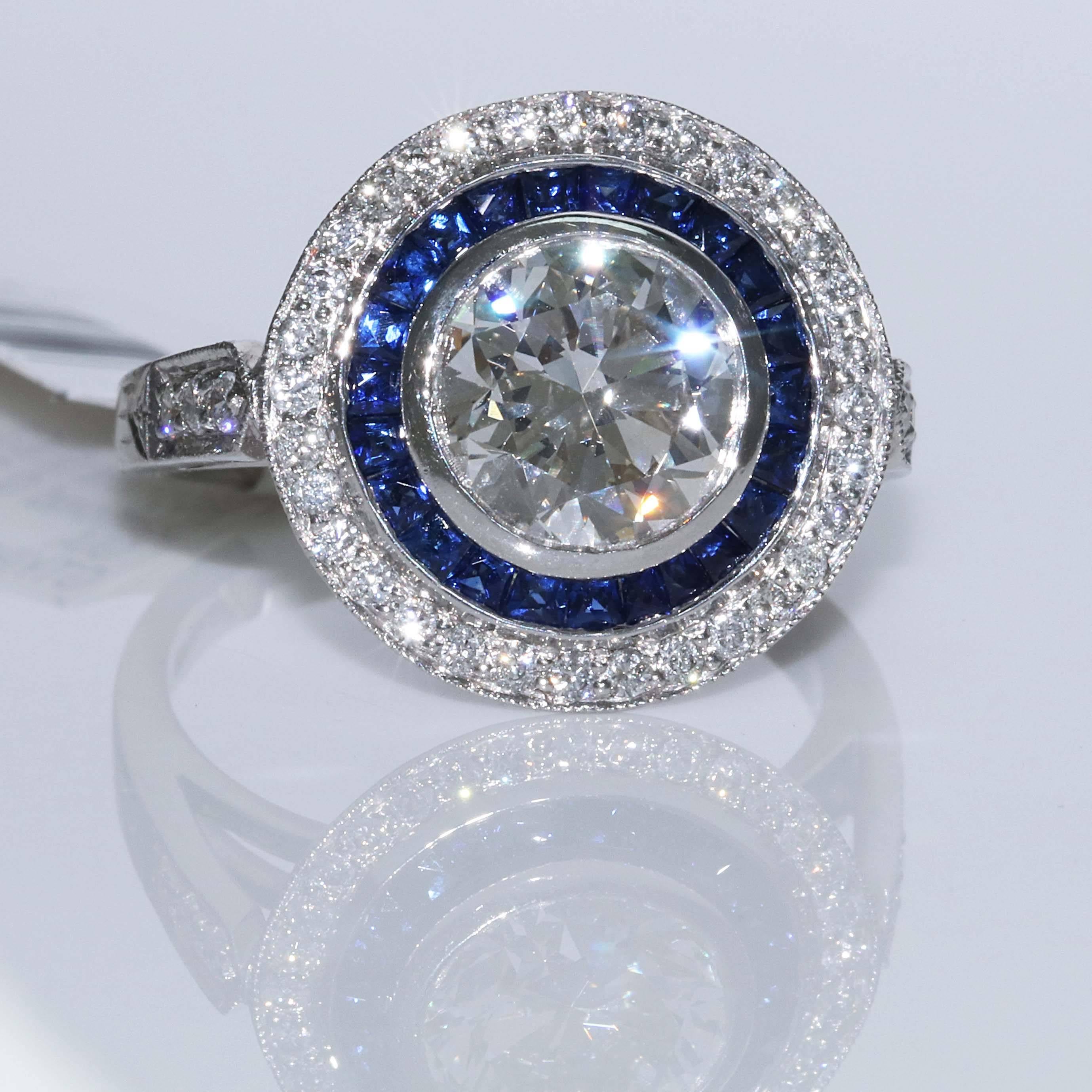 What a perfect engagement ring or fashion ring. This ring plays both parts. In the center is an exquisite GIA Certified 2.18 carat i-Si1 round brilliant diamond. Around the center diamond is .63 carats of blue sapphires. These sapphires all match in