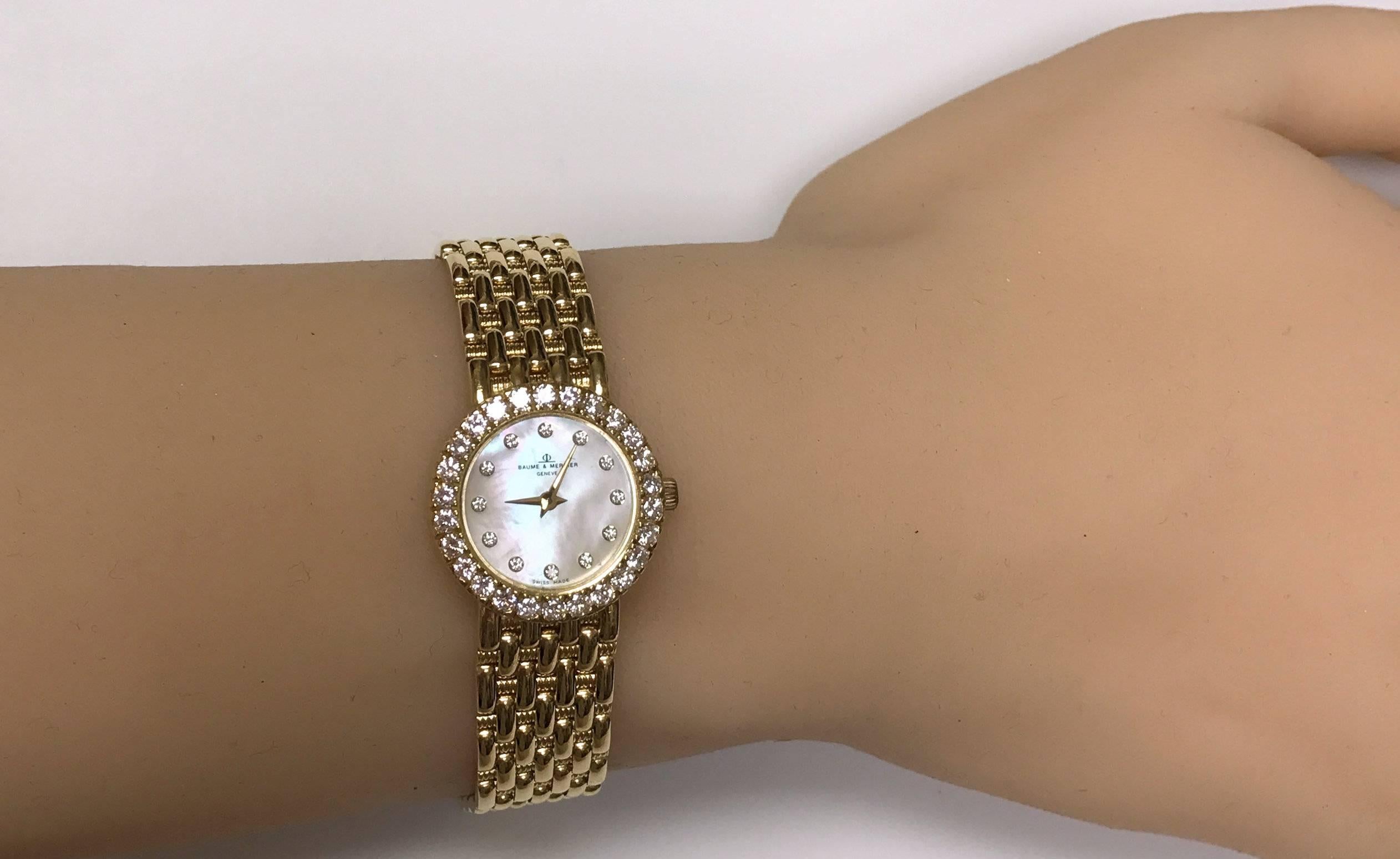 Mother of pearl diamond dial and bezel 18 Karat yellow gold Baume Mercier wrist watch.  Woven textured and high polish bracelet.  38 round diamonds approximately 1.00 carat total weight VS, G. 27.6 dwt. Clasp closes firmly, no stretch in the