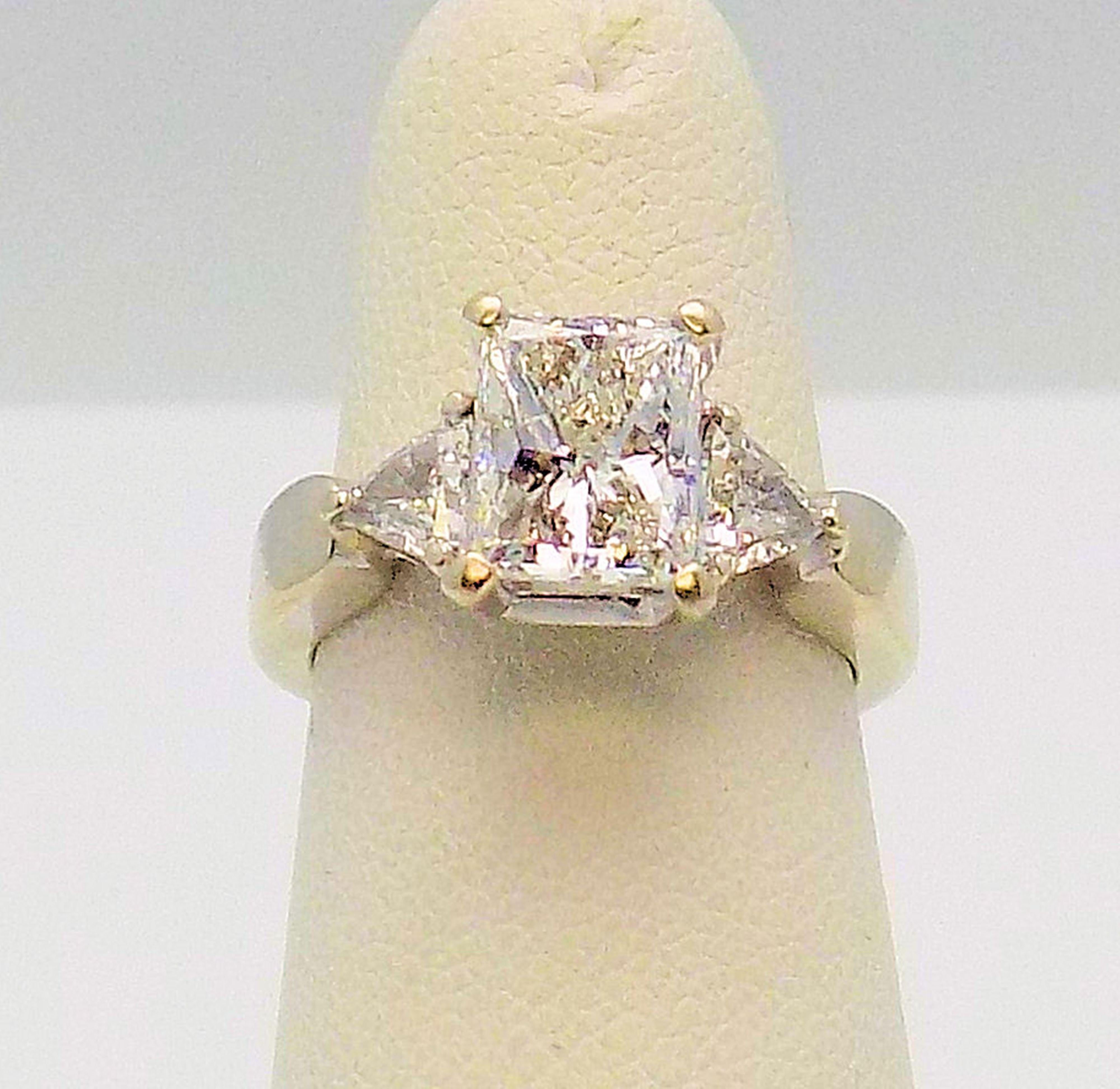 Lovely 14 Karat White Gold Engagement Ring featuring 1 Radiant Cut Diamond 1.52 Carat SI-2, I, and 2 Trilliant Cut Diamonds 0.46 Carat Total Weight SI, I-J. Finger Size 5; 3.2 DWT or 4.98 Grams.

The Jewelry Gallery offers ring sizing (at additional