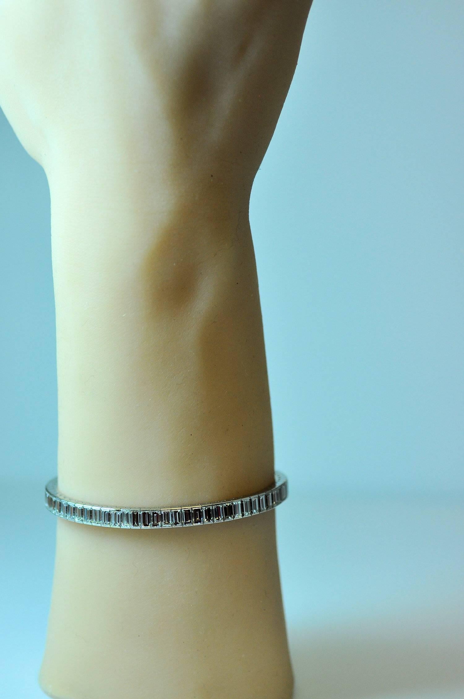 Sleek, elegant, classic.  Worn on its own or with other bracelets, this classic is stunning. 18K white gold line bracelet channel set with fine baguette cut diamonds.  69 baguette cut diamonds weighing a total of approximately 13.60 ct. total weight