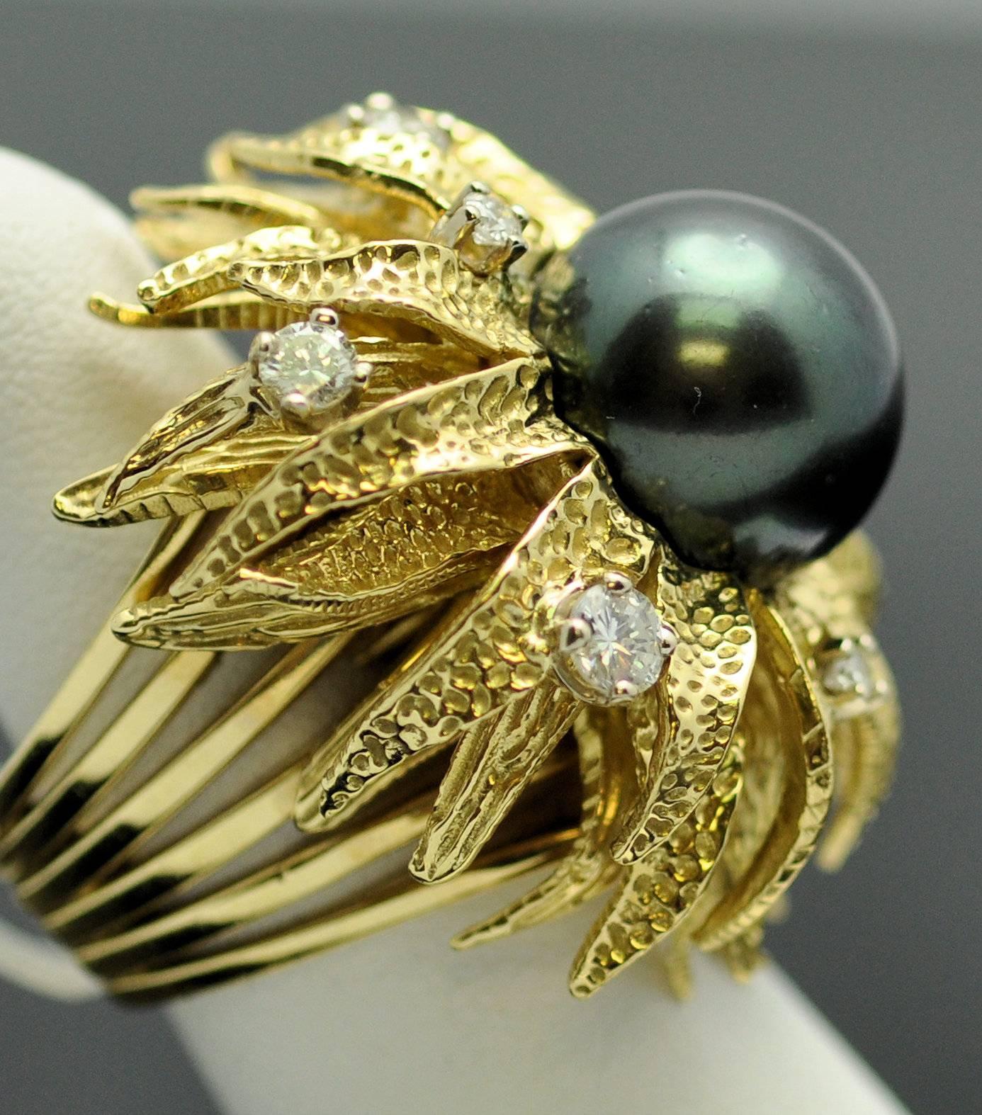 Large and lovely Tahitian pearl ring in floral motif set with 13.5 mm. pearl of lovely peacock green-black, the most desirable color of black pearl, natural color, cultured pearl.  It nestles in the center of a flower set with 7 round diamonds