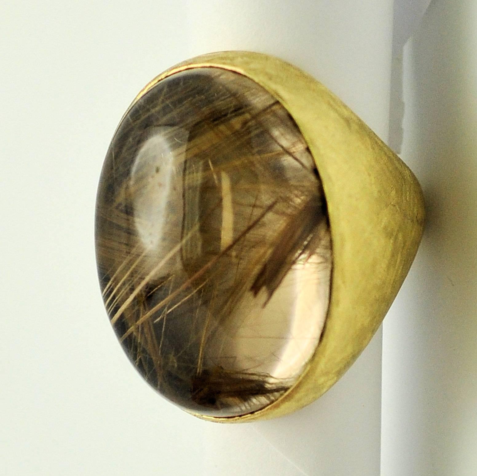 Imposing Florentine finish 18K yellow gold ring with bezel set large oval rutilated quartz cabochon.  Well made squared shank makes the ring more stable.  The rutile is well-distributed throughout the stone.  27.7 dwt gross wt. Sizing bumps in the