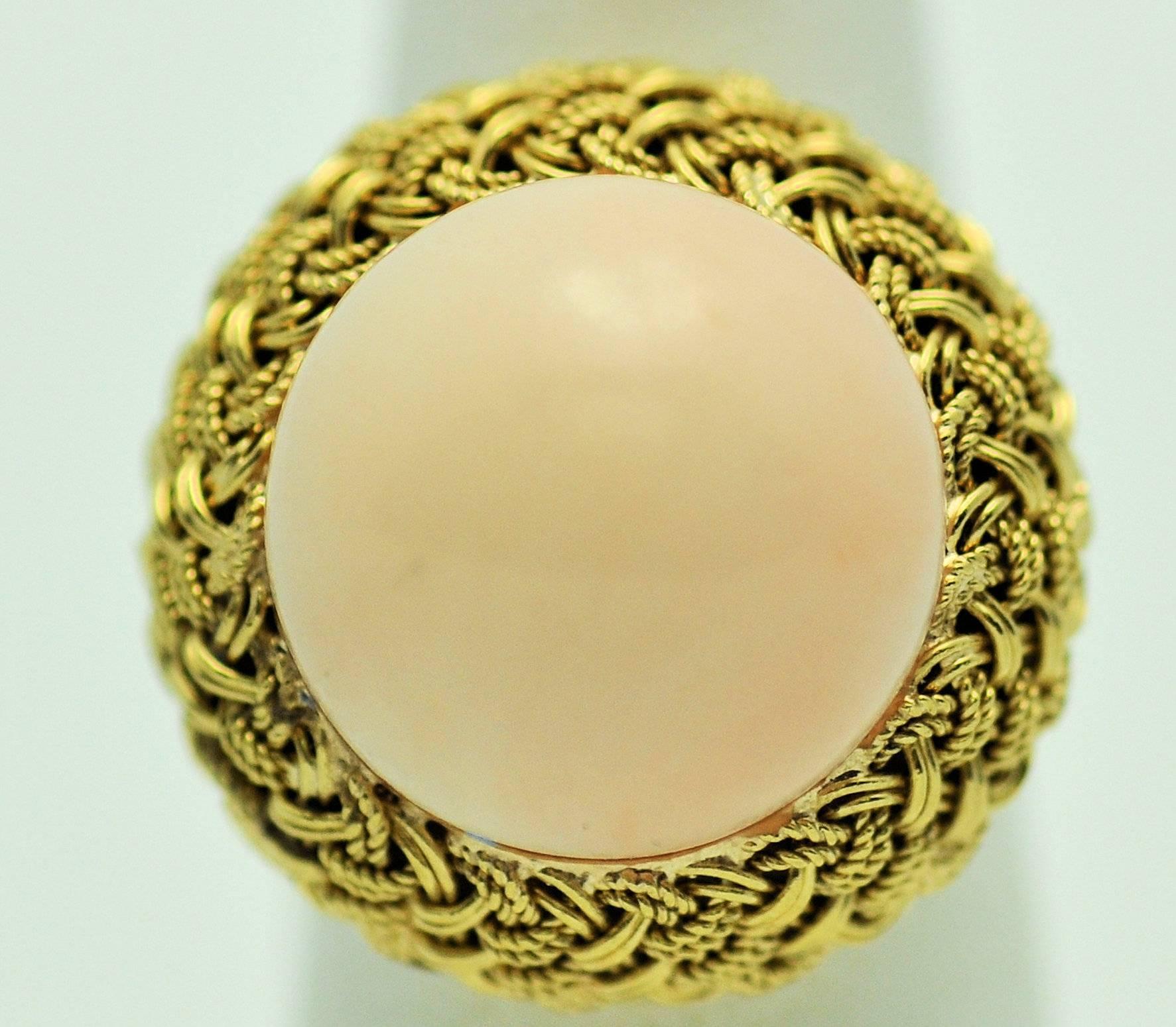 18Karat yellow gold angel skin coral ring with woven gold border and center of light pink coral.  Nice, high dome cabochon of coral, excellent surface.  Even color.  Completely natural, not dyed or treated.  Coral measures 15 mm. in diameter. 
