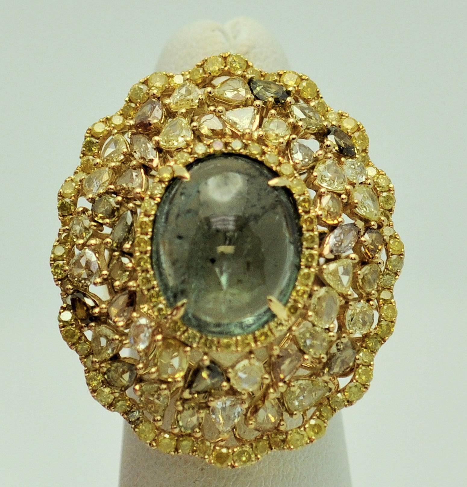 18Karat ring with center cabachon of light green tourmaline measuring 14 x 10 mm.  Yellow diamonds surround the tourmaline and outer border of the ring. Colored diamonds set in the field. 
95 yellow round diamonds 1.00 carat total weight
46 mixed