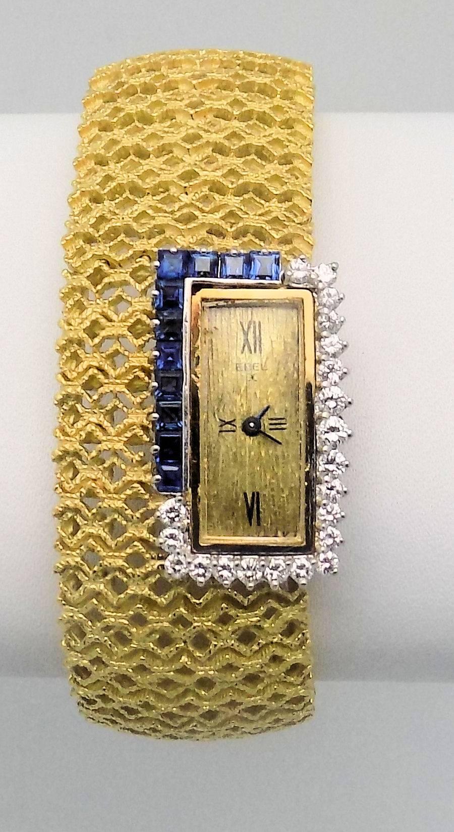18 Karat yellow gold bracelet wrist watch set with square cut sapphires and round brilliant cut diamonds.  Textured dial with Roman- numerals and heavily textured openwork bracelet. Double prong clasp is very secure. Safety chain added. Watch