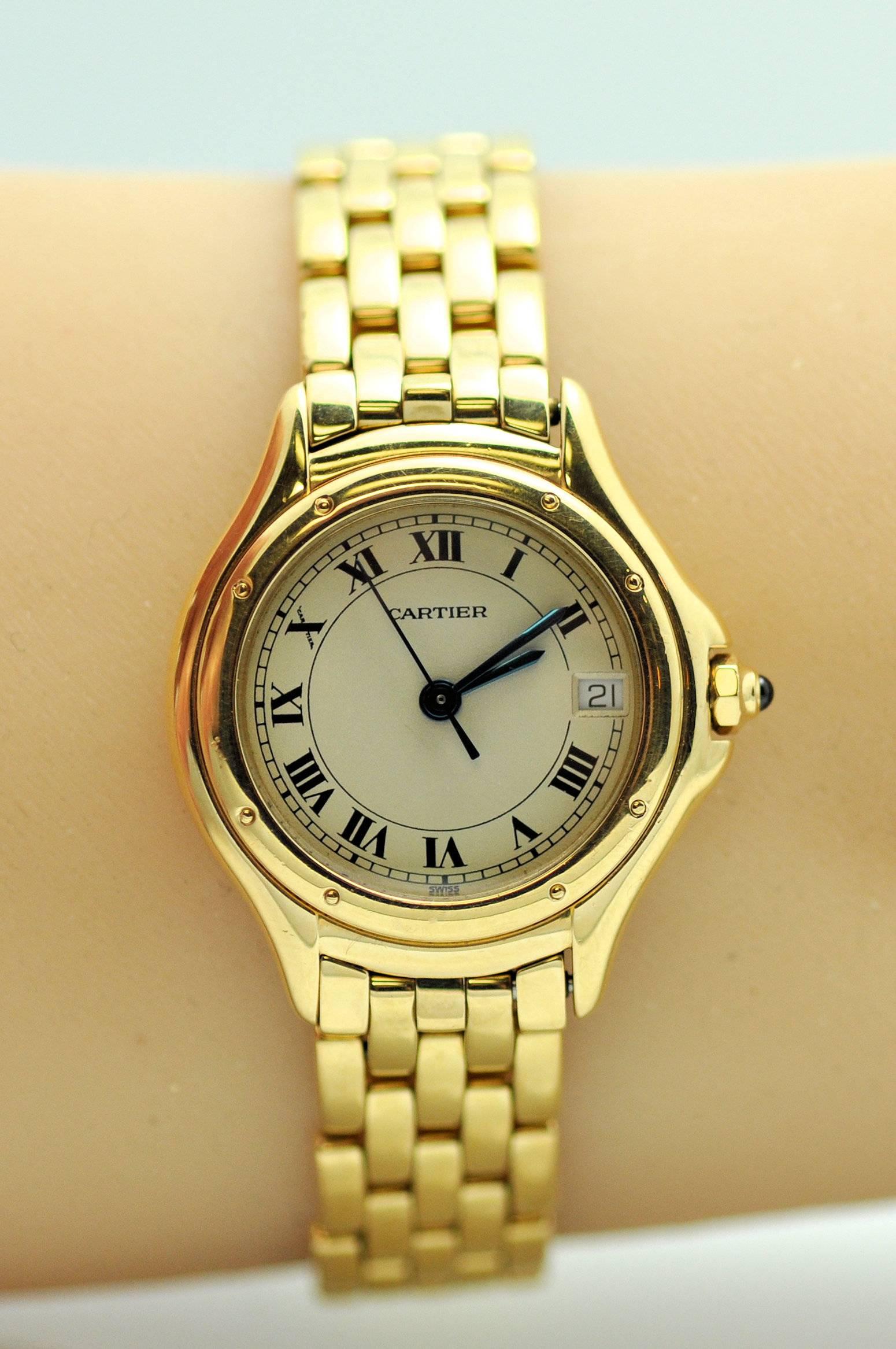 18 Karat yellow gold lady's Cougar model wrist watch.  Cream color dial with Roman numerals and date.  Synthetic sapphire dial.  Quartz. Double deployant clasp. Watch length can be reduced. 