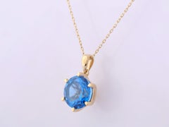 Collana con ciondolo solitario in oro giallo 14 carati con topazio blu svizzero rotondo, montato a 6 griffe