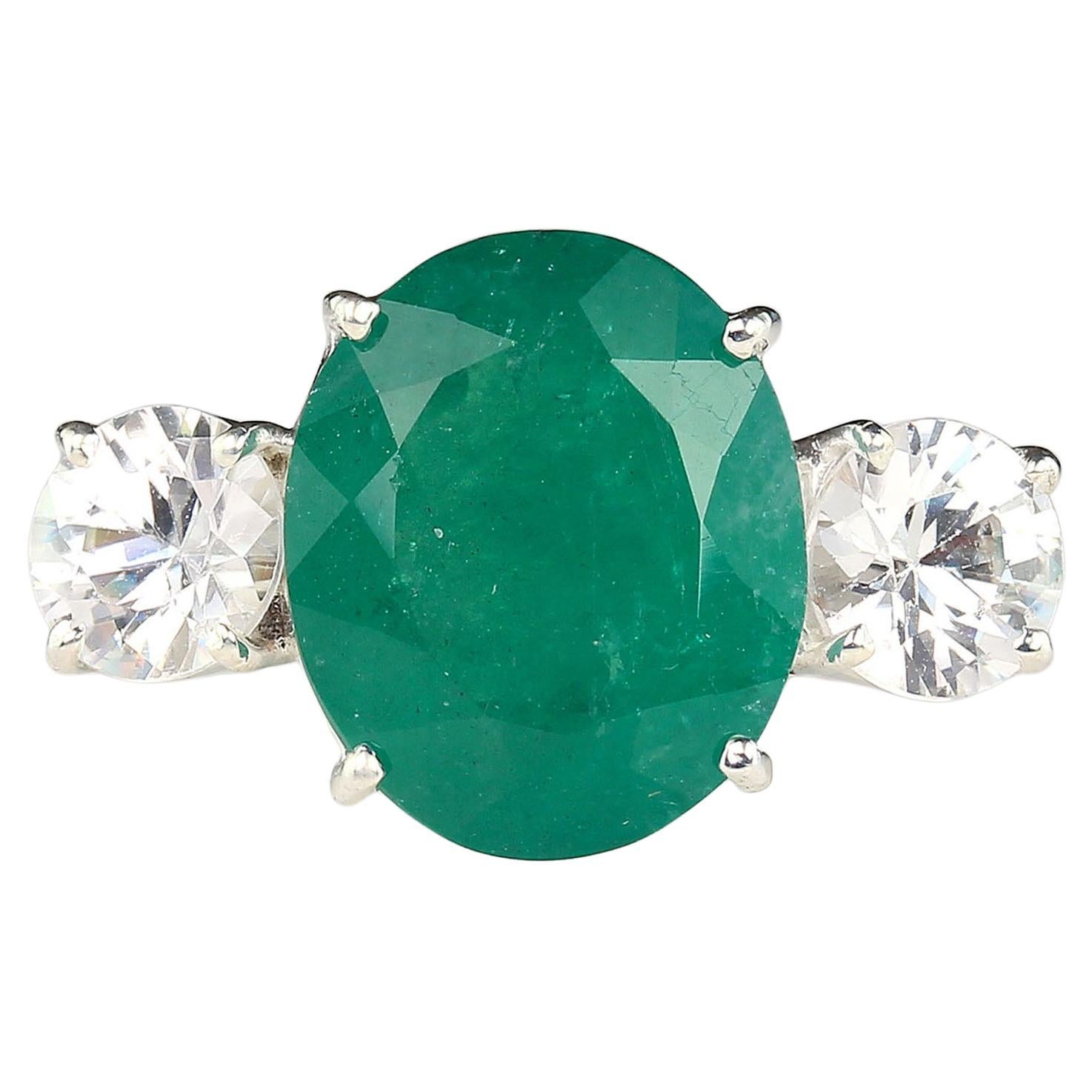 Magnificent dinner ring of huge 6.46 carat oval Brazilian Emerald accented with two round genuine Zircons, 2.58 carats total weigh set in Sterling Silver. This Emerald came straight from one of our favorite suppliers in Belo Horizonite, Minas