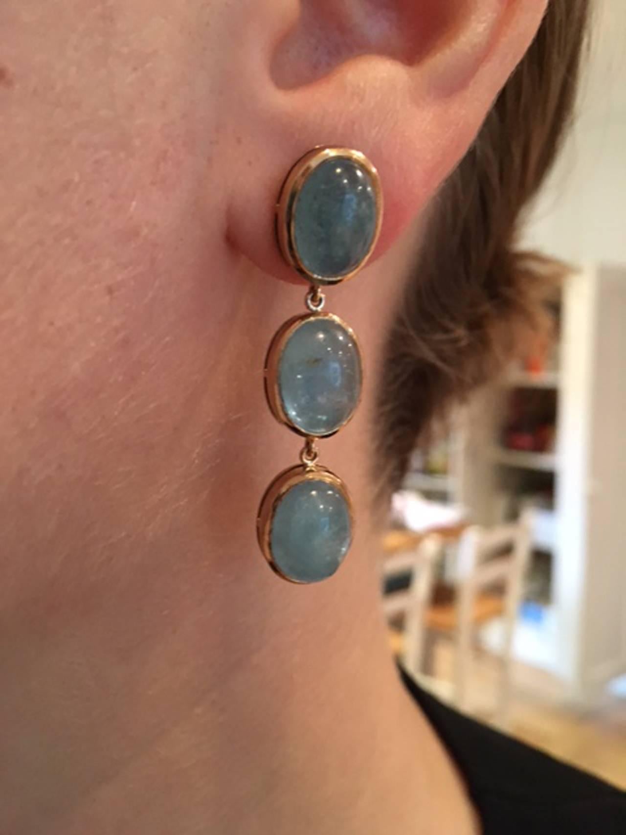 Three stone Aquamarine drop earrings set in rub-over style in 9kt yellow gold.
Size 4.3 x 8 mm.  Stones 11 x 9 mm.  These are post settings.