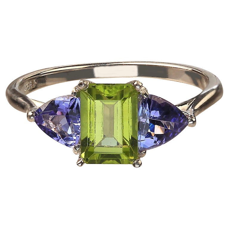 Delightful ring of emerald cut sparkling Peridot accented with triangles of glittering Tanzanites. Wear these gems with everything and enjoy how the green and purple works with your entire wardrobe.  The emerald cut Peridot is approximately 1.30