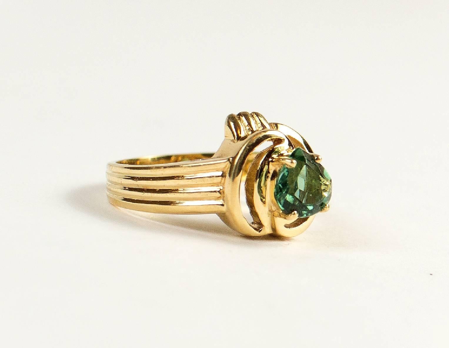   Lovely apple green very sparkly Brazilian fat pear shape tourmaline (approximately 6x5mm) set in a swirl of 18kt yellow gold.  This Brazilian handmade ring has a generous amount of 18kt yellow gold in a creative setting to enhance its wonderful