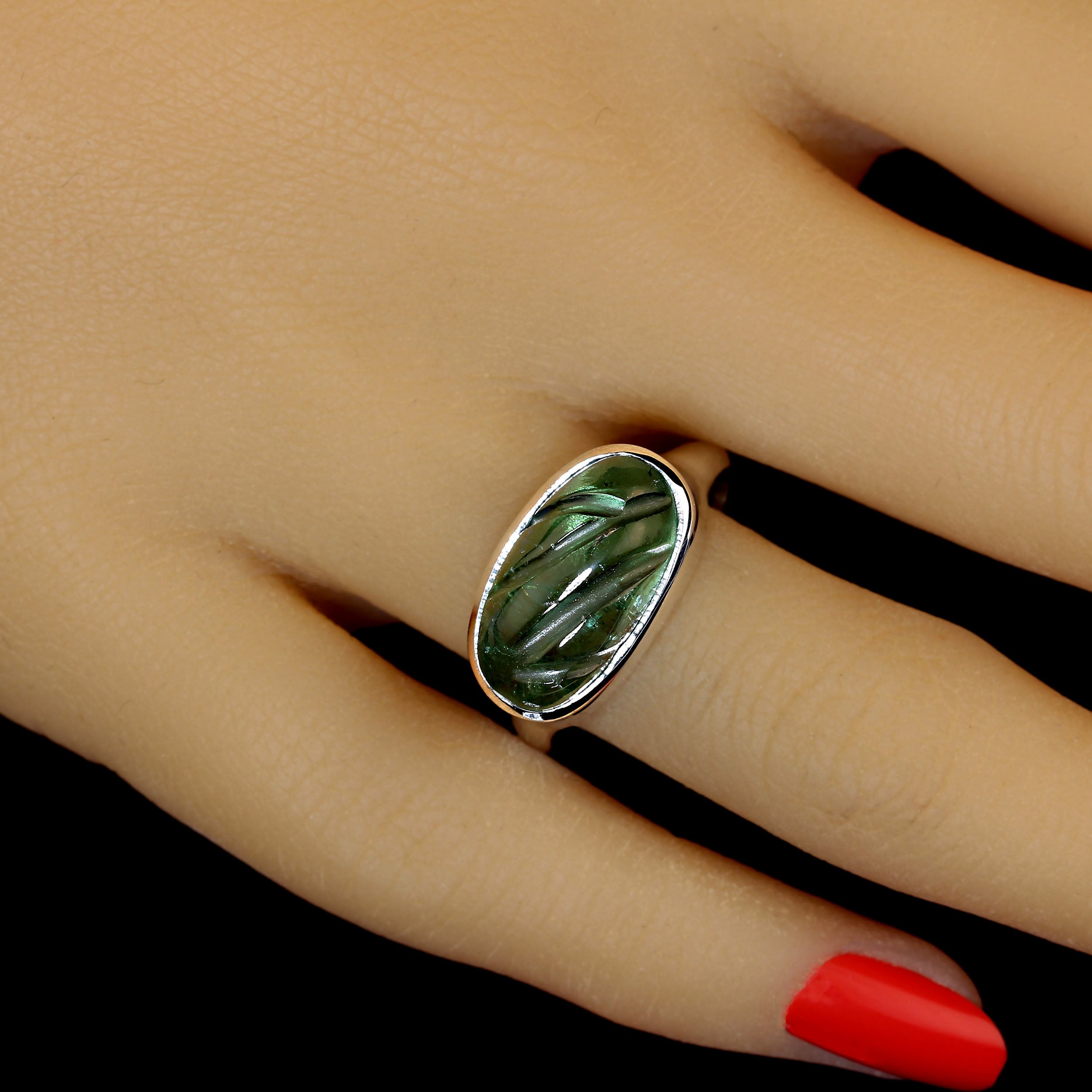 Einzigartiger, geschnitzter grüner Turmalin in einem maßgefertigten Sterling Silber Ring.  Die Ost-West-Fassung der Lünette ist wunderschön.  Das glatte Sterlingsilber liegt elegant in der Hand. Die Schönheit des Turmalins und sein breites Spektrum