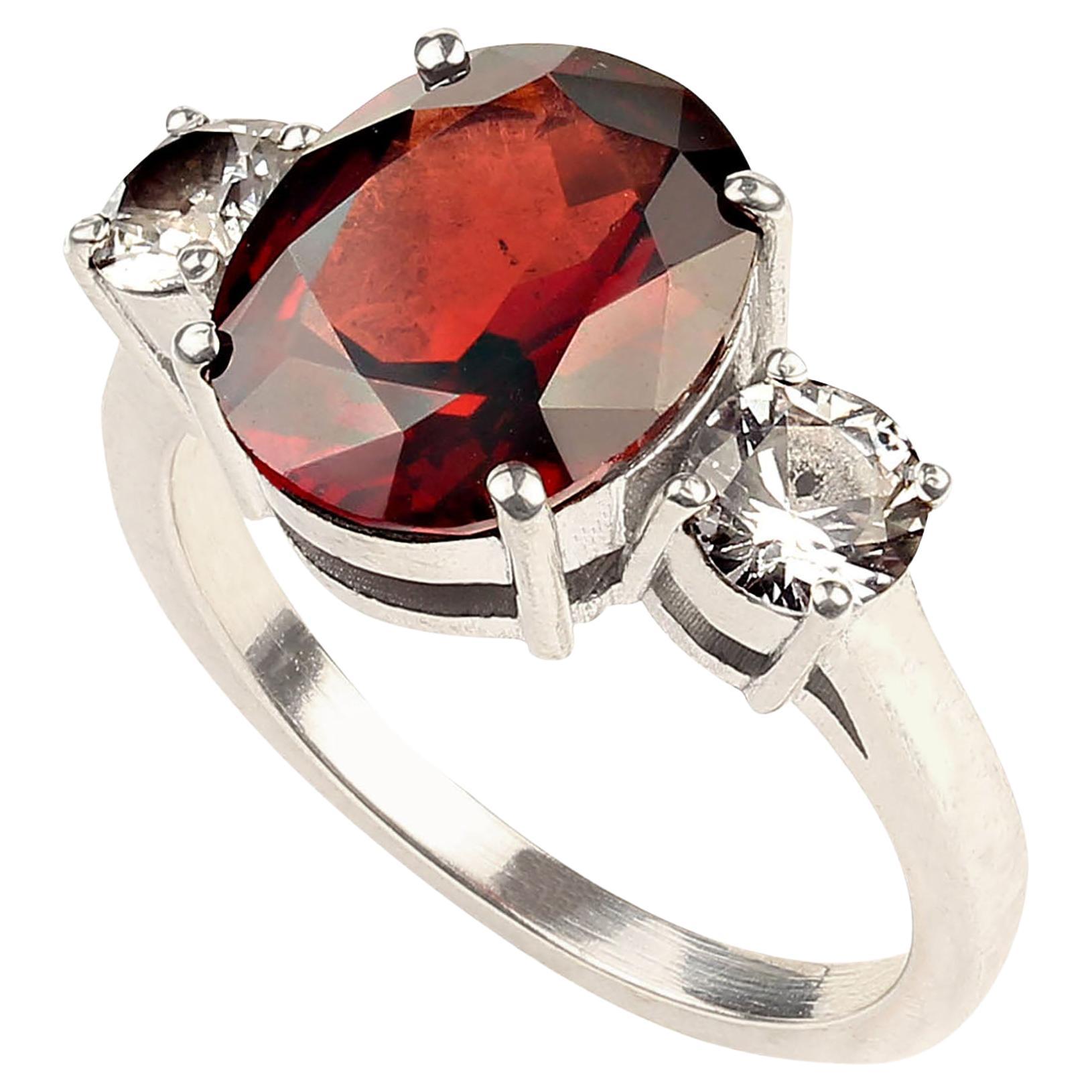 Classic three stone ring of gorgeous Garnet and sparkling white sapphires. This large oval  garnet weighs in at 5.03ct. The two white round sapphires are total weight of 1.06ct. These gemstones are set in Sterling Silver. This is that great ring you