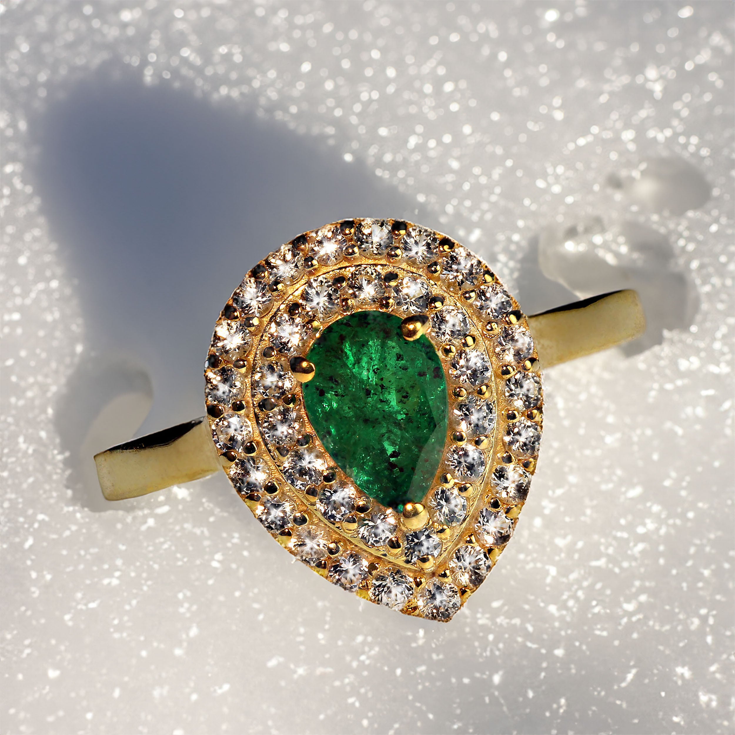 Elegant pear shaped brazilian Emerald surrounded by two rows of white Sapphires, all set in gold rhodium over Sterling Silver ring. This lovely deep green brazilian Emerald weighs in at 0.73 carats.  The ring itself is a generous 15 x 12 MM, making