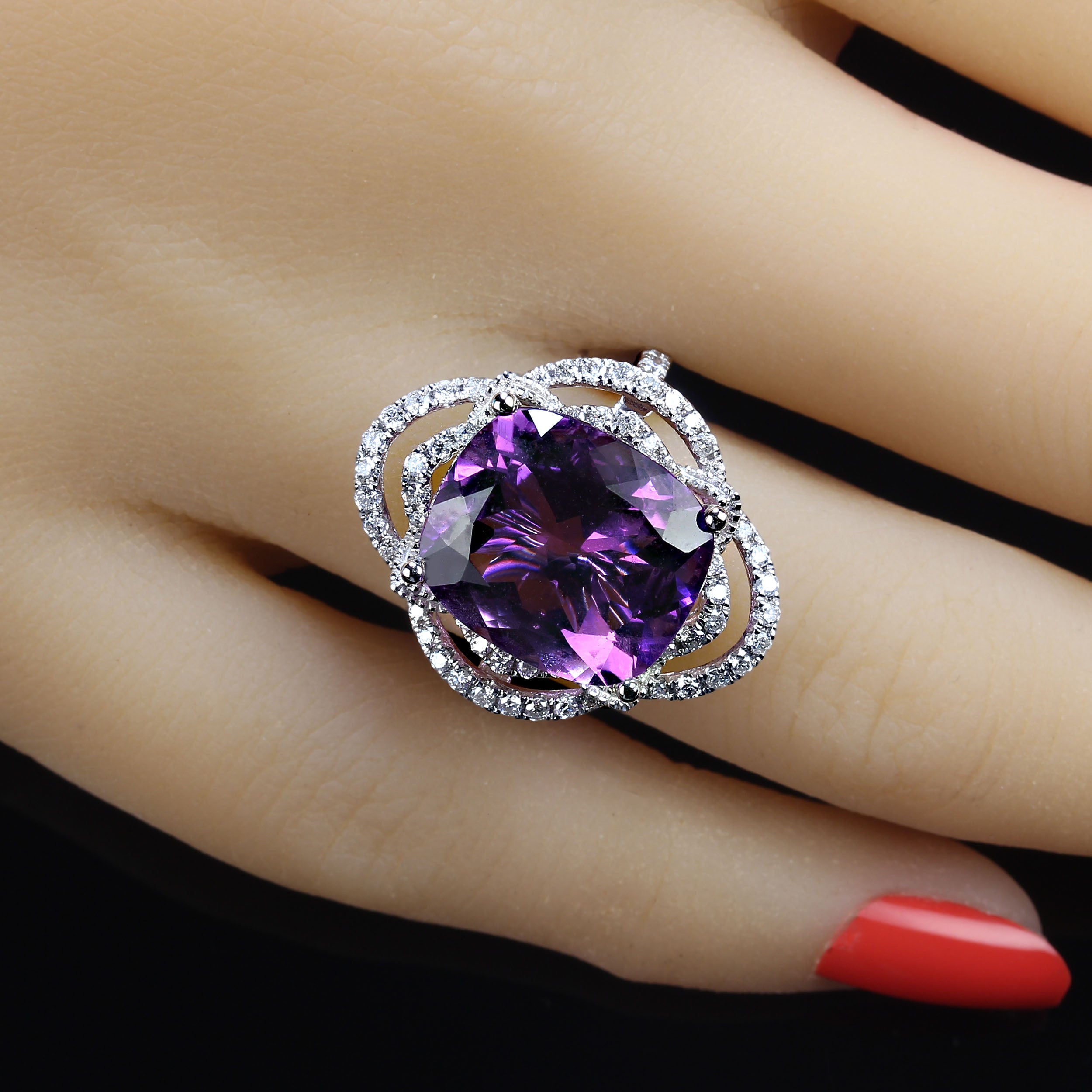 Delightful cocktail ring of cushion cut Amethyst, 7.63ct, in 14K white gold setting featuring 0.61ct of Diamonds. The two looping halos of Diamonds create an elegant and dramatic setting for this lovely Amethyst. The diamonds continue down the top