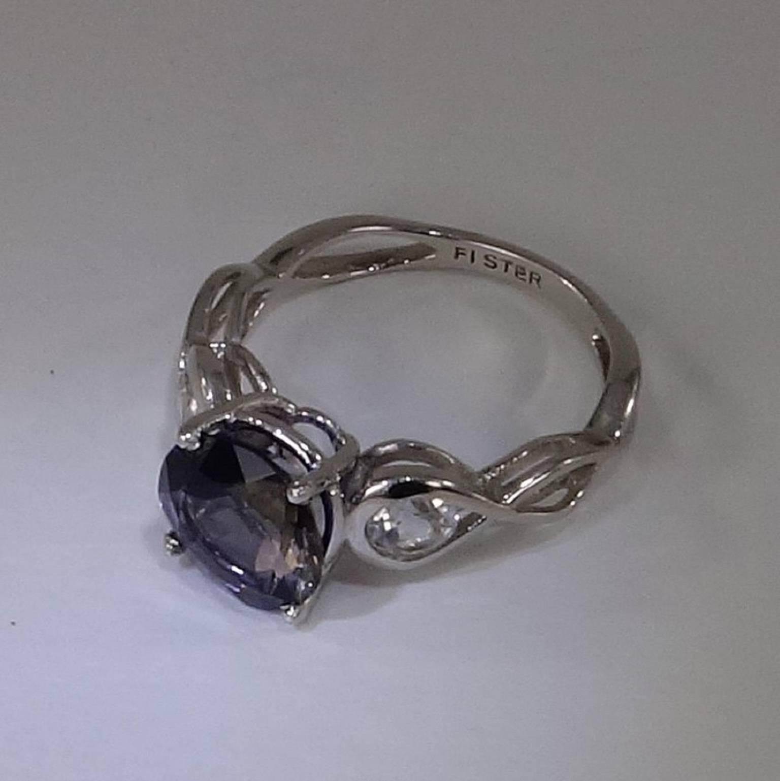Lovely Sterling Silver ring of round blue Iolite accented with Silver Topaz. Iolite gemstones are trichroic and will flash gray or straw depending on the angle at which they are viewed. The Iolite is 2.09ct and the Silver Topaz total weight is 0.60