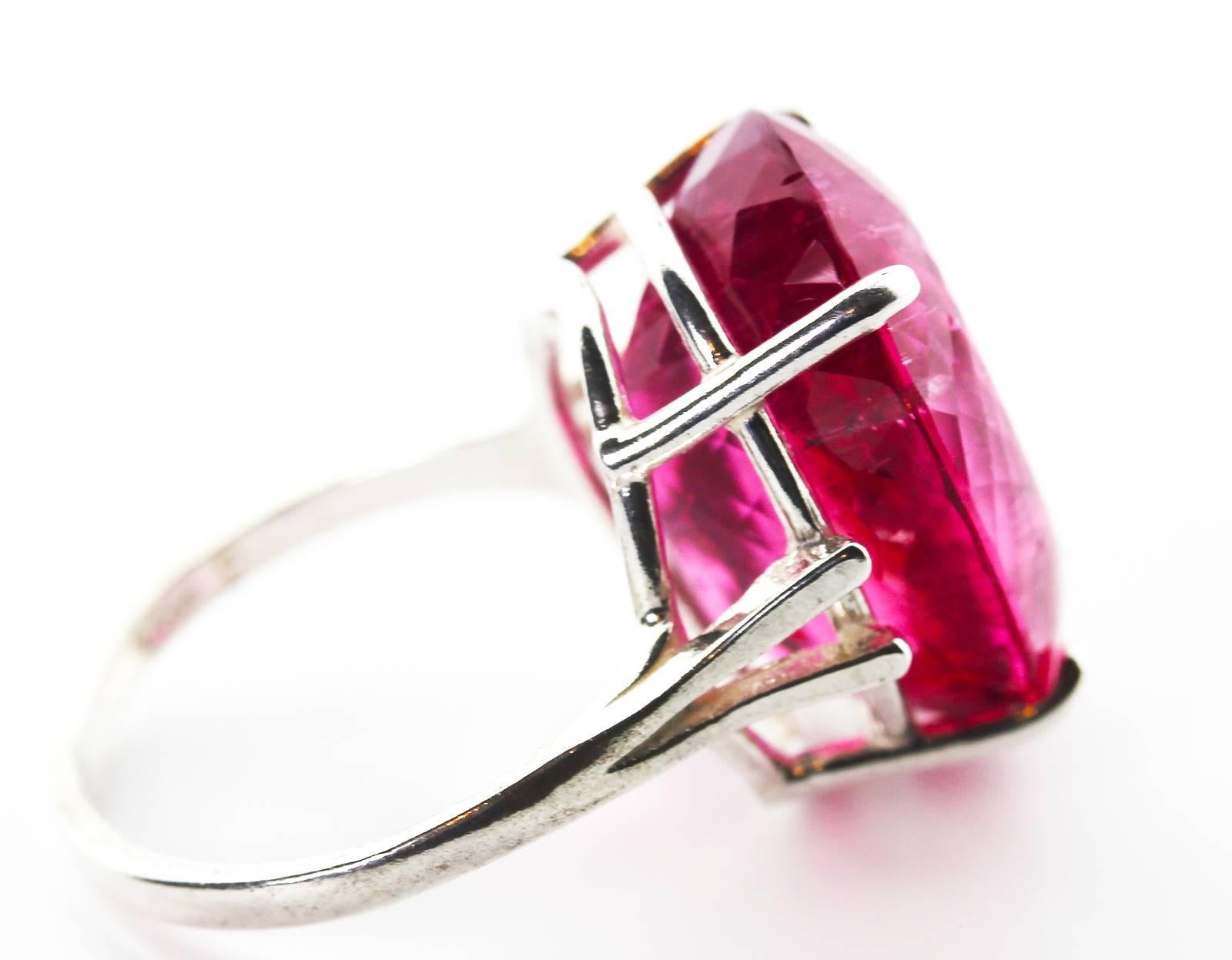 This flawless looking spectacular glittering rare 19.59 Carat oval Rubelite from the famous mine near Ouro Preto in Brasil measures 19.7 mm x 14.2 mm and is set in a Sterling Silver ring size 6.75 (easily sizable).