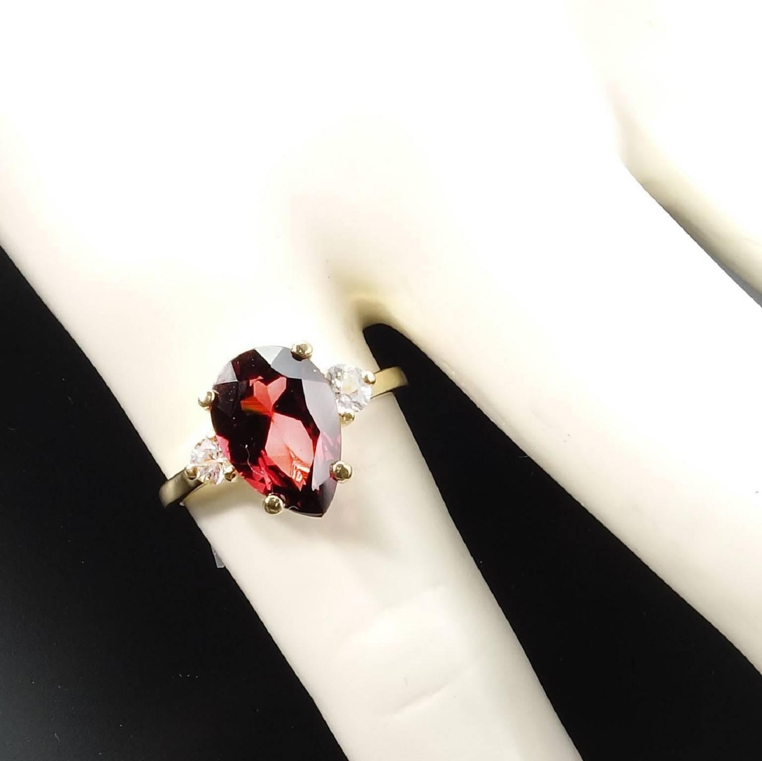  Custom made sparkling, pear shape, Brazilian Rhodolite Garnet enhanced with two White Sapphires set in a classic 14K Yellow gold ring.  This Rhodolite Garnet is exceptionally bright and sparkling. It is 2.86 carats which is large for this bright a