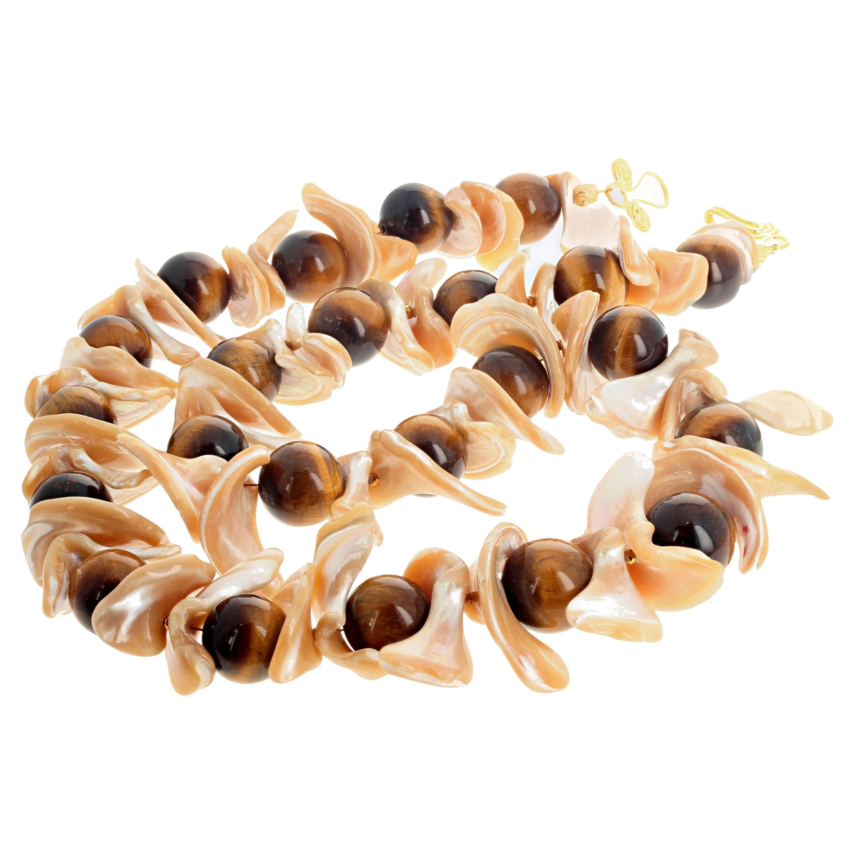 Enormi e fluttuanti conchiglie di perle naturali splendenti abbracciano questi bellissimi occhi di tigre naturali lucidissimi in questa collana lunga 28 pollici con chiusura a gancio placcata oro facile da usare.  L'occhio di tigre è rotondo di