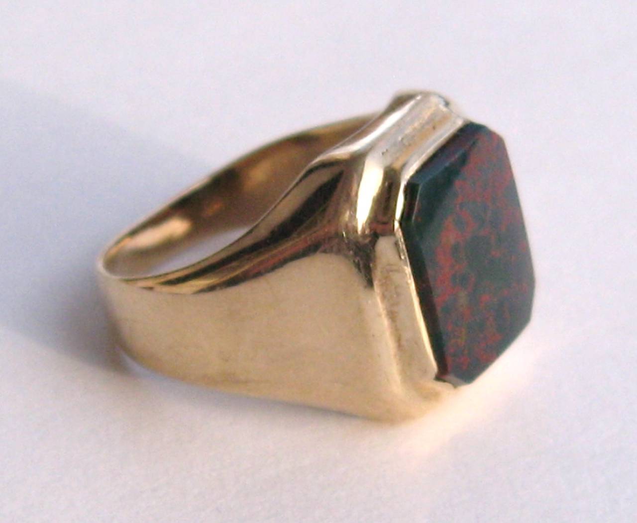 The mounting is classic and simple, set in 14K Yellow Gold 
wide shoulders of gold, tapering down at the inside of the finger.  The flat bloodstone is bezel-set in the center.  The stone is a deep deep green as a good bloodstone should be, with