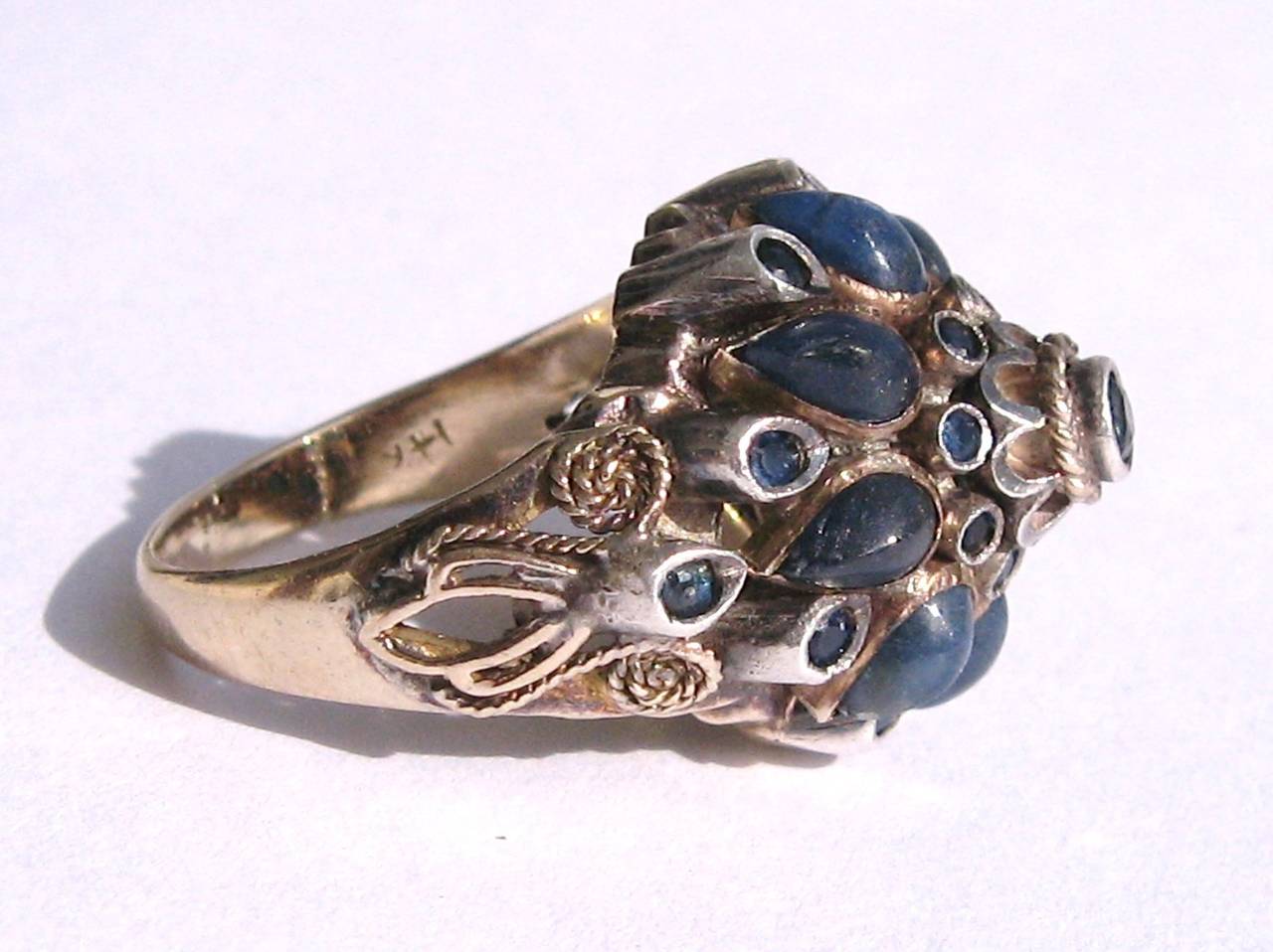 Stacked up with Cabochons sapphires. Intricate detailing on the shank. Set in 14K Yellow Gold. The Ring is a 5.5.  However, it can be size by us or you jeweler. This is out of a massive collection of Contemporary designer clothing as well as Hopi,