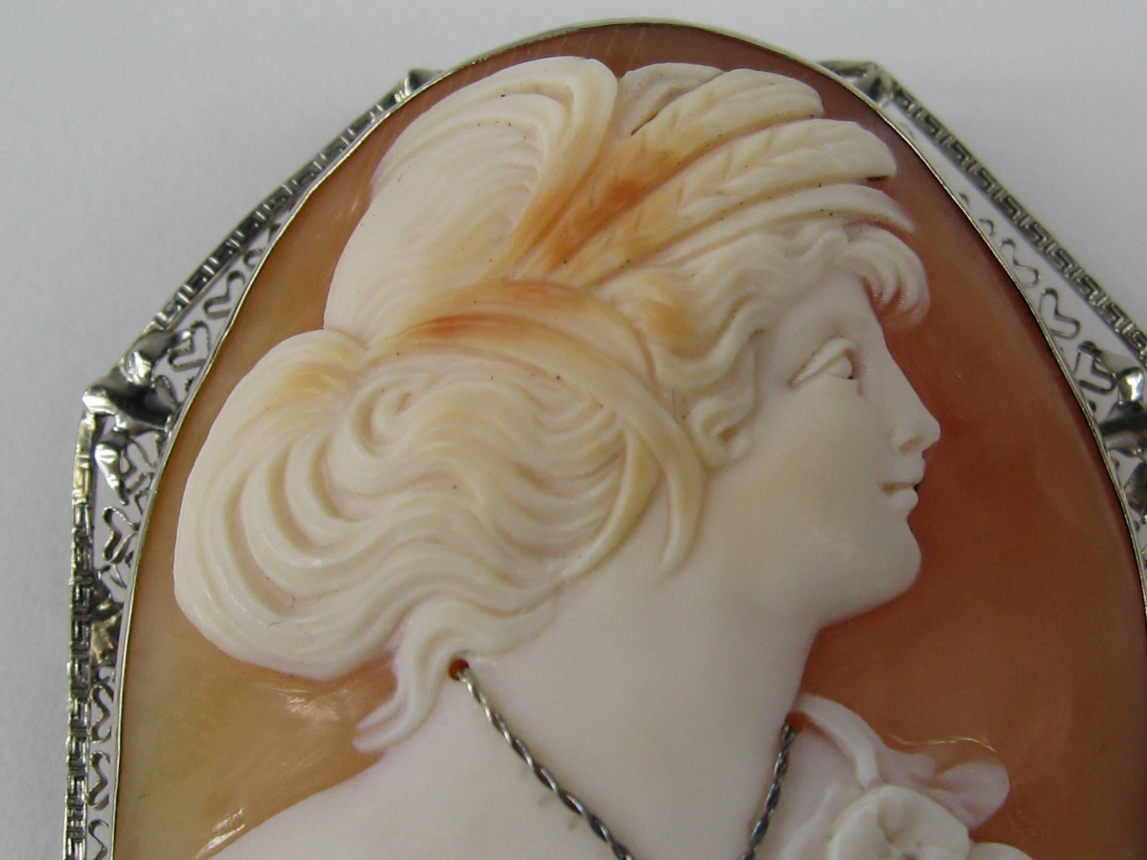 This is stunning in person. Set in 14K White Gold. Large Shell Cameo. Side profile of a Lady dressed in her finest, Diamond necklace adorns her neck. This is a Brooch as well as a pendant with a fold down Bale, Measuring 2.36 in x 1.86 in. This is