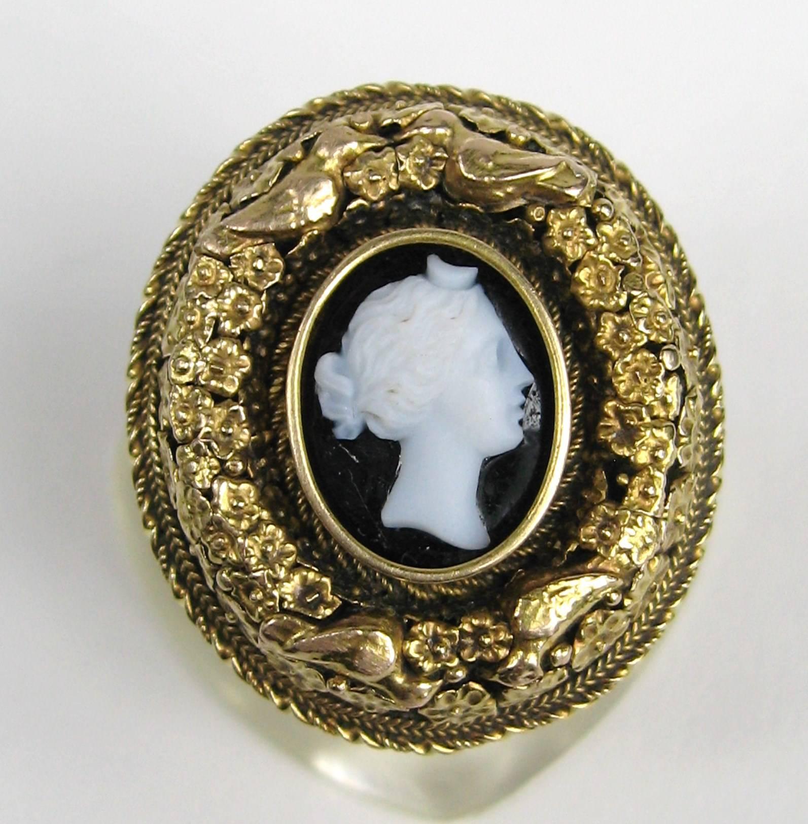 Stunning floral and birds make up the surround on this 14K gold ring. Center is a Victorian woman. Victorian later soldered onto a modern shank. The ring is large in scale measuring 1.10 in x 1 in, Ring is a size 7 and can be sized by your jeweler