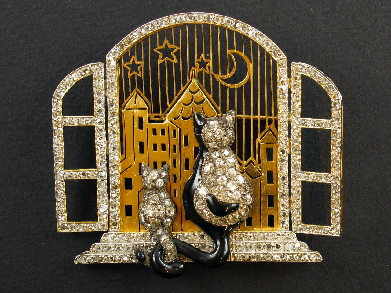 A unique yellow gold and diamond brooch depicting an opened window with two enameled and encrusted cats overlooking the horizon. 1940 c.a. Convertible into a pendent. 1940 c.a.