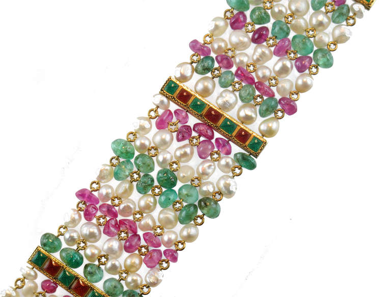 A Ribbon bracelet in yellow gold, natural pearl, emeralds and rubies. Interspaced at regular intervals with yellow gold bars links decorated with alternating green and red enamel squares.