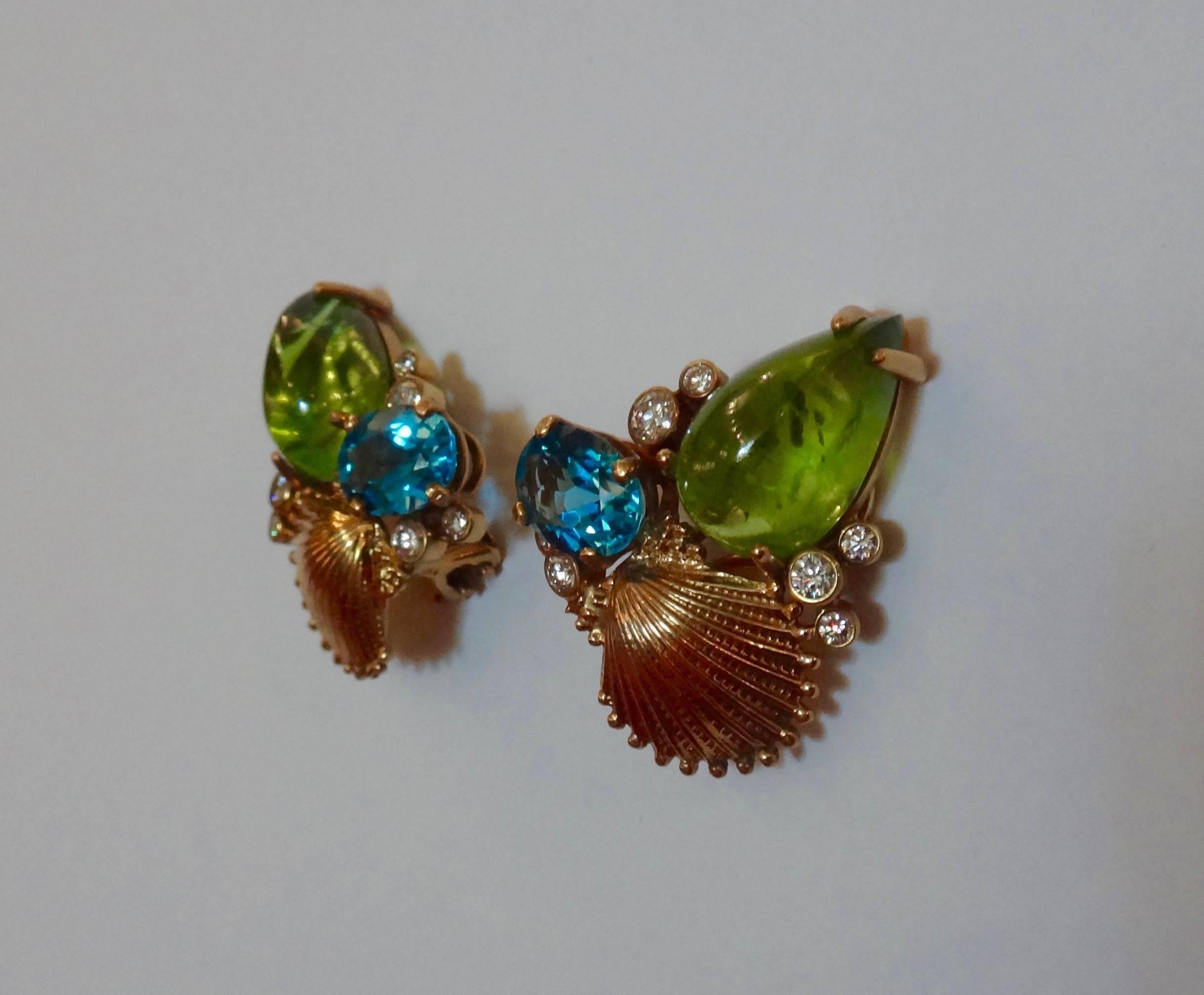 A fine and perfectly matched pair of cabochon peridots (2 at 16.37 carats), two faceted Swiss blue topaz (2 at 4.10 carats) and 14 bezel set diamonds at .77 carats are combined  with 18k yellow gold sculpted shells in these 