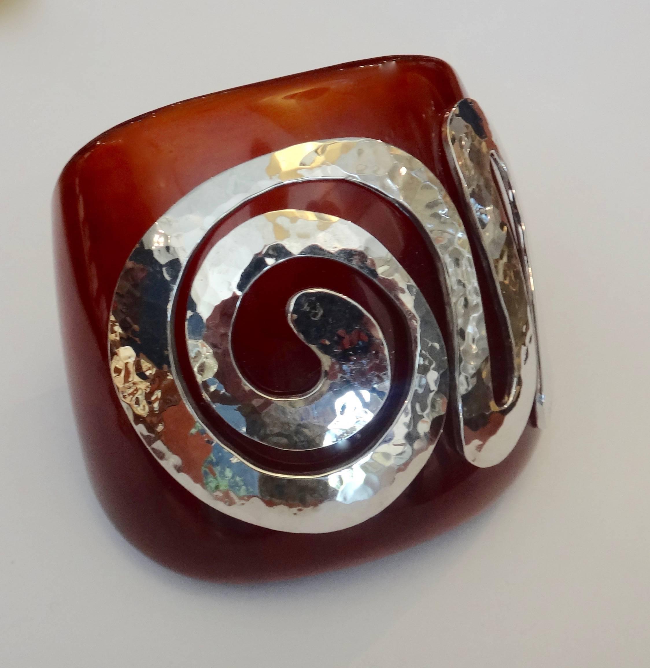 This amber colored vintage bakelite cuff is embellished with a spiral of forged sterling silver.  The silver has been rhodium plated to prevent tarnishing.  6 inch inside circumference.  