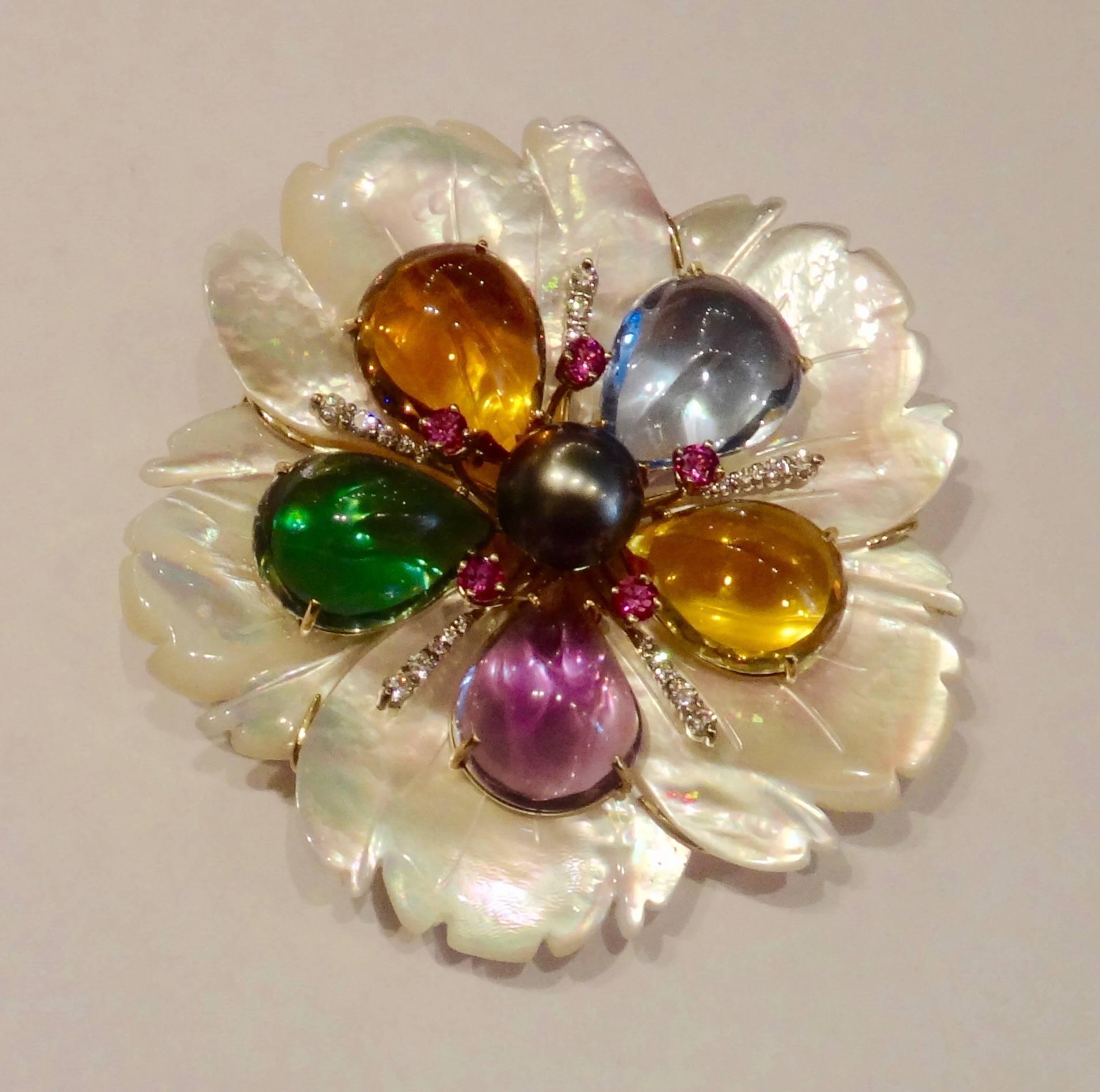 One-of-a-kind carved mother-of-pearl flower is decorated with pear shaped amethyst, citrine, blue topaz and green amethyst along with hot pink sapphires, a generously sized, gem quality Tahitian pearl and brilliant cut, white diamonds.  The piece